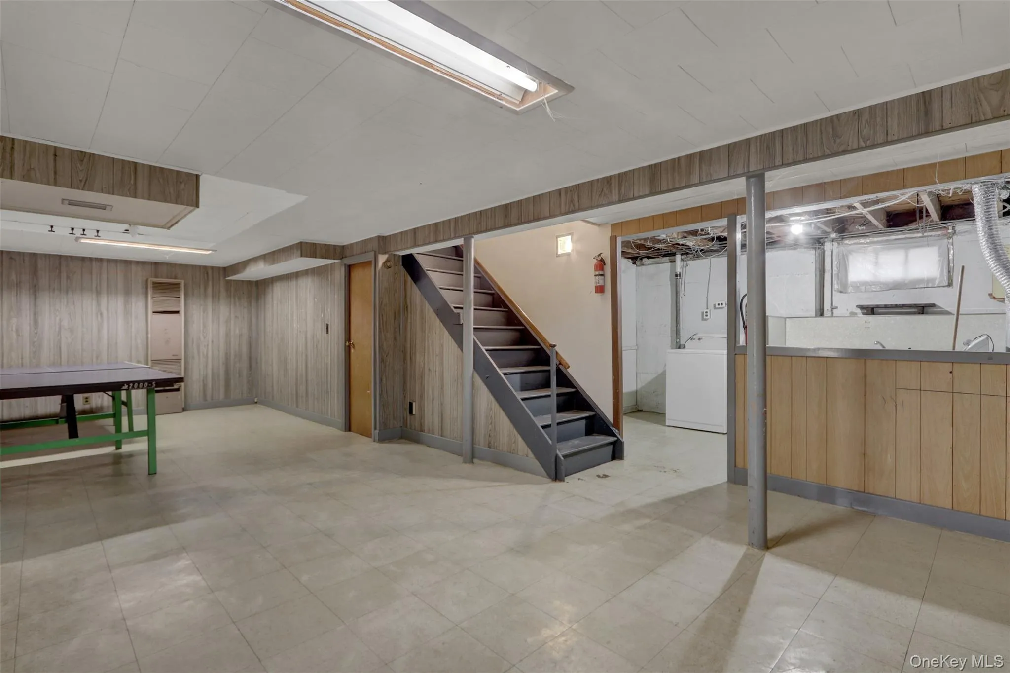 Finished below grade area with wood walls, stairway, washer / clothes dryer, and light floors Finished below grade area with wood walls, stairway, washer / clothes dryer, and light floors