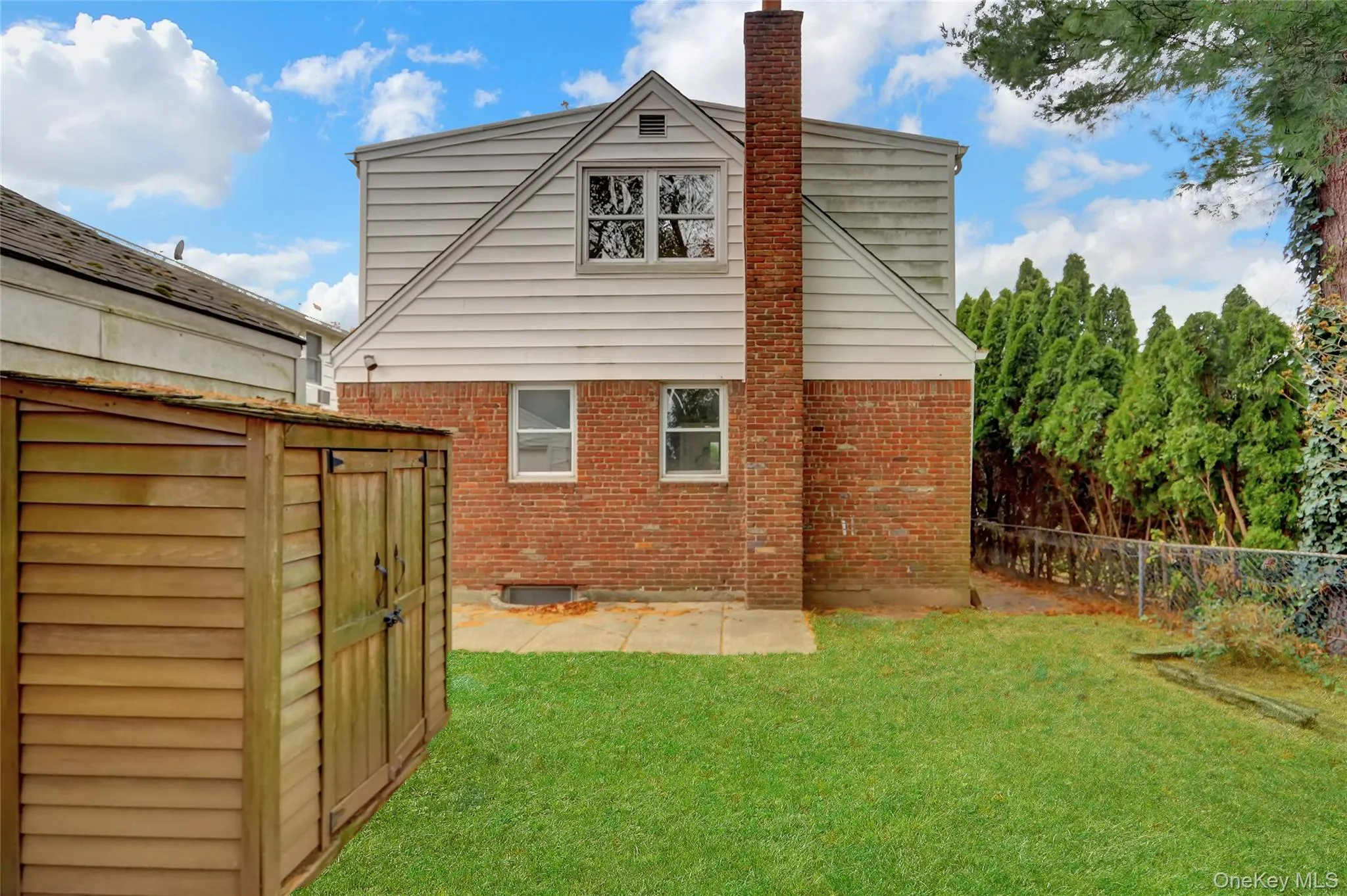 Back of property with brick siding, a fenced backyard, a chimney, and a storage shed Back of property with brick siding, a fenced backyard, a chimney, and a storage shed