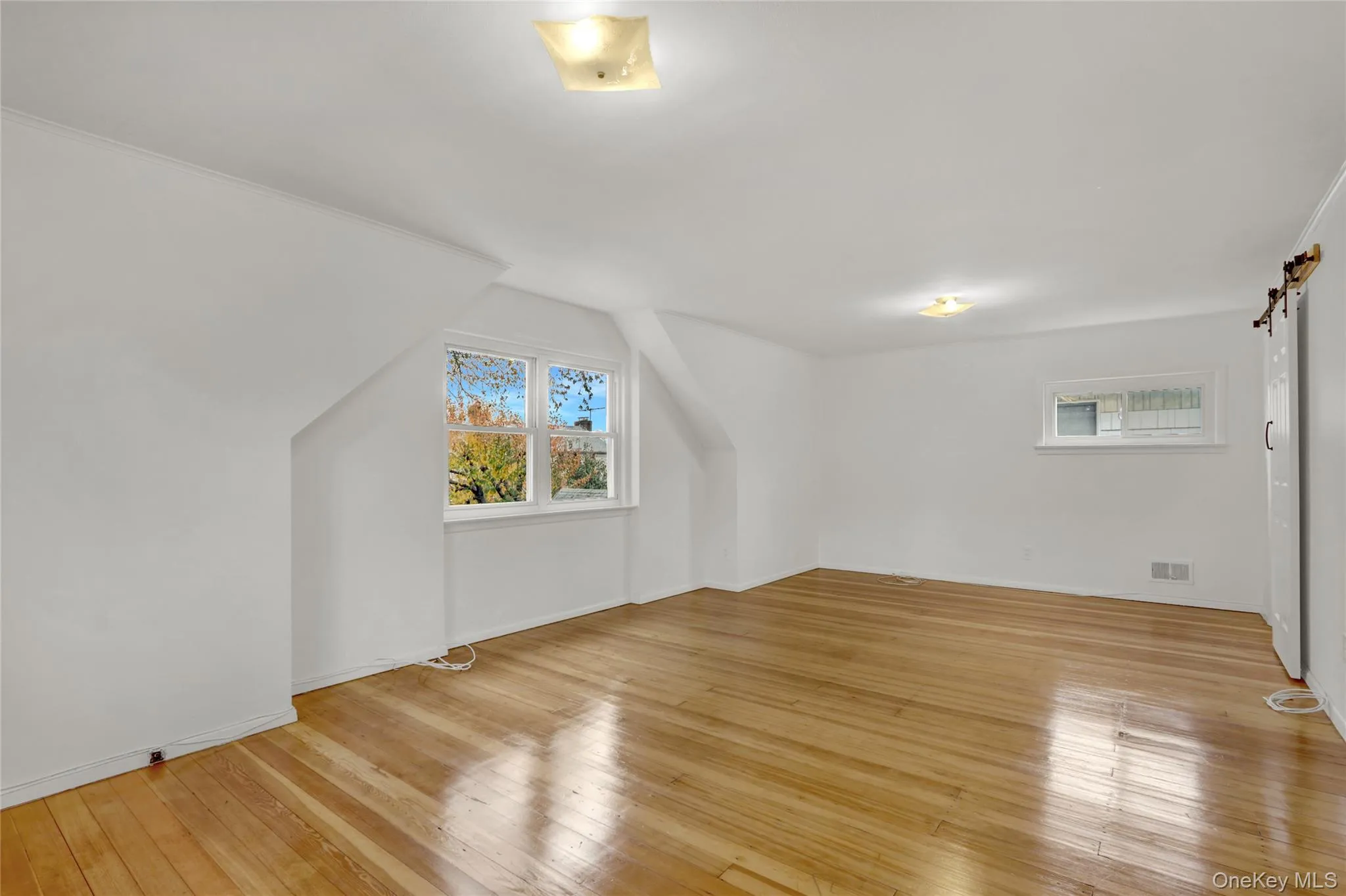 large bedroom on 2nd floor featuring a barn door and light wood floors large bedroom on 2nd floor featuring a barn door and light wood floors