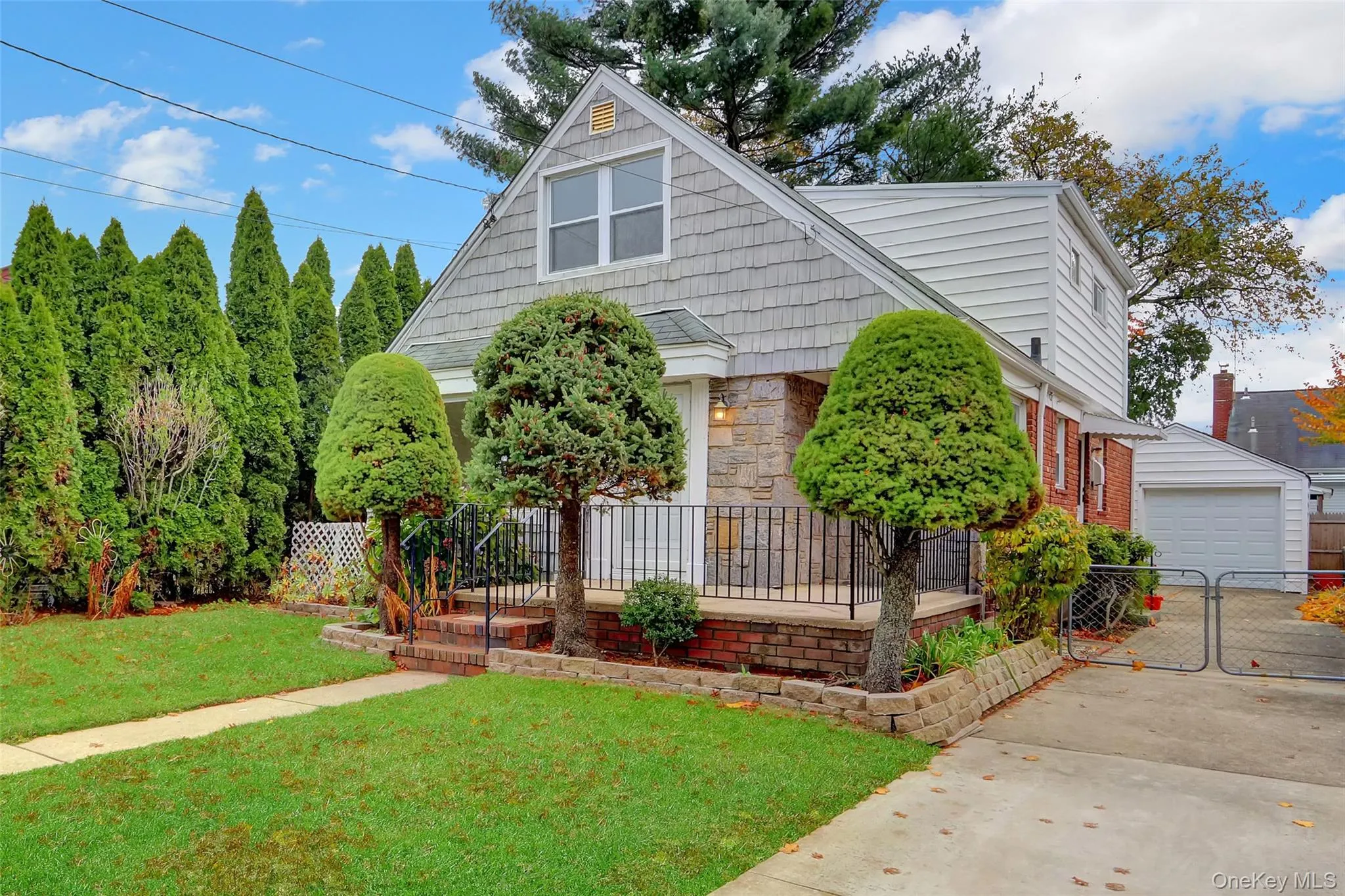 Cape-style home featuring stone siding, a garage, and an outdoor structure Cape-style home featuring stone siding, a garage, and an outdoor structure