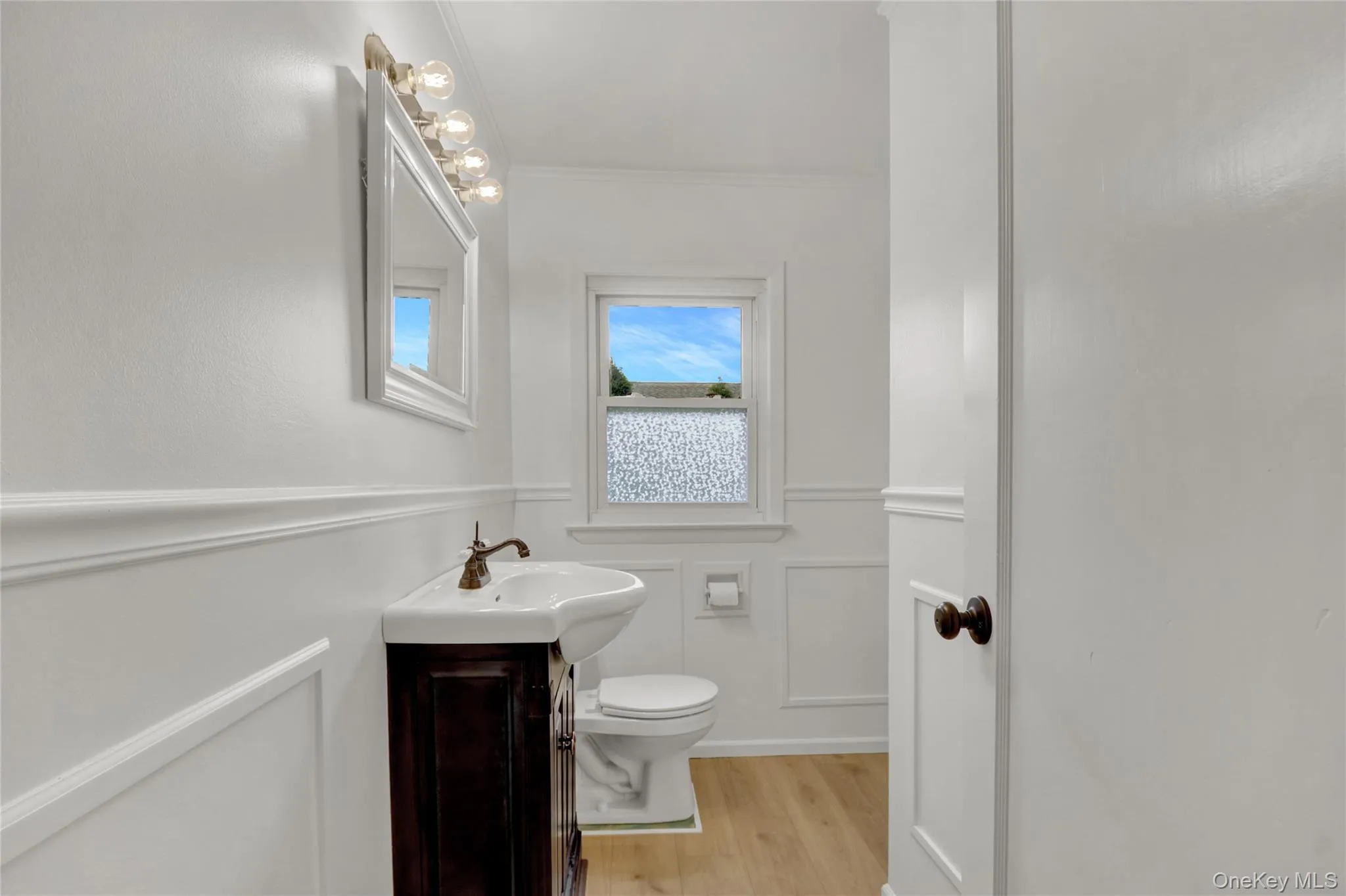 1/12 Bathroom on 2nd floor with a decorative wall, vanity, wainscoting, light wood-style flooring, and ornamental molding 1/12 Bathroom on 2nd floor with a decorative wall, vanity, wainscoting, light wood-style flooring, and ornamental molding