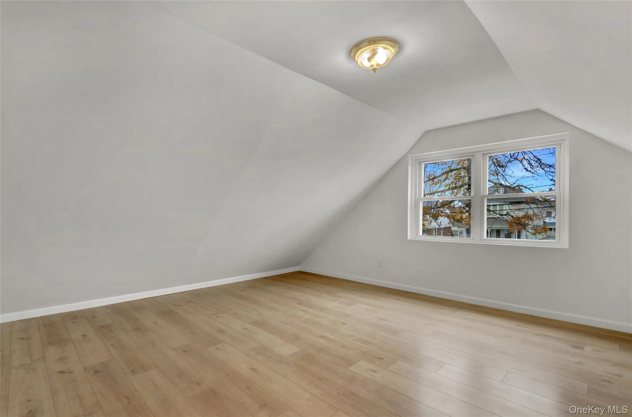 Additional living space with light wood-style floors and vaulted ceiling Additional living space with light wood-style floors and vaulted ceiling