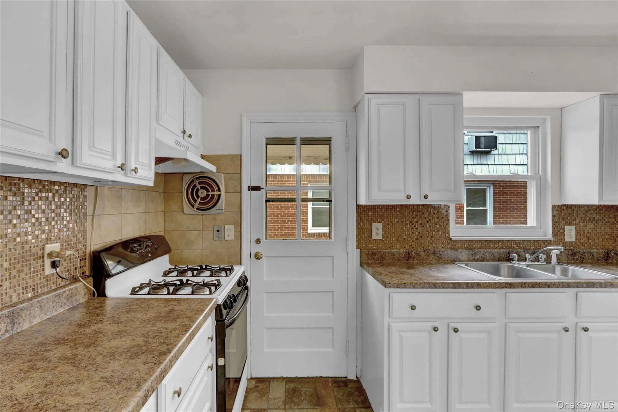 Kitchen featuring white cabinets, range with gas cooktop, and decorative backsplash Kitchen featuring white cabinets, range with gas cooktop, and decorative backsplash