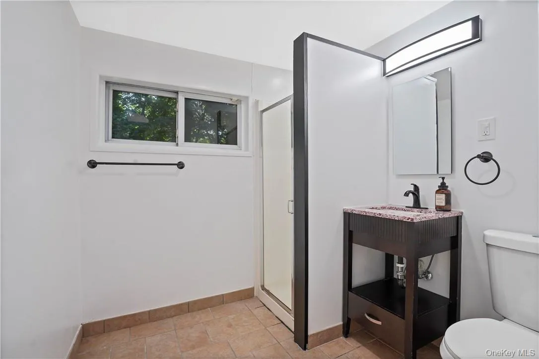 Bathroom with a shower with door, tile flooring, vanity, and toilet Bathroom with a shower with door, tile flooring, vanity, and toilet