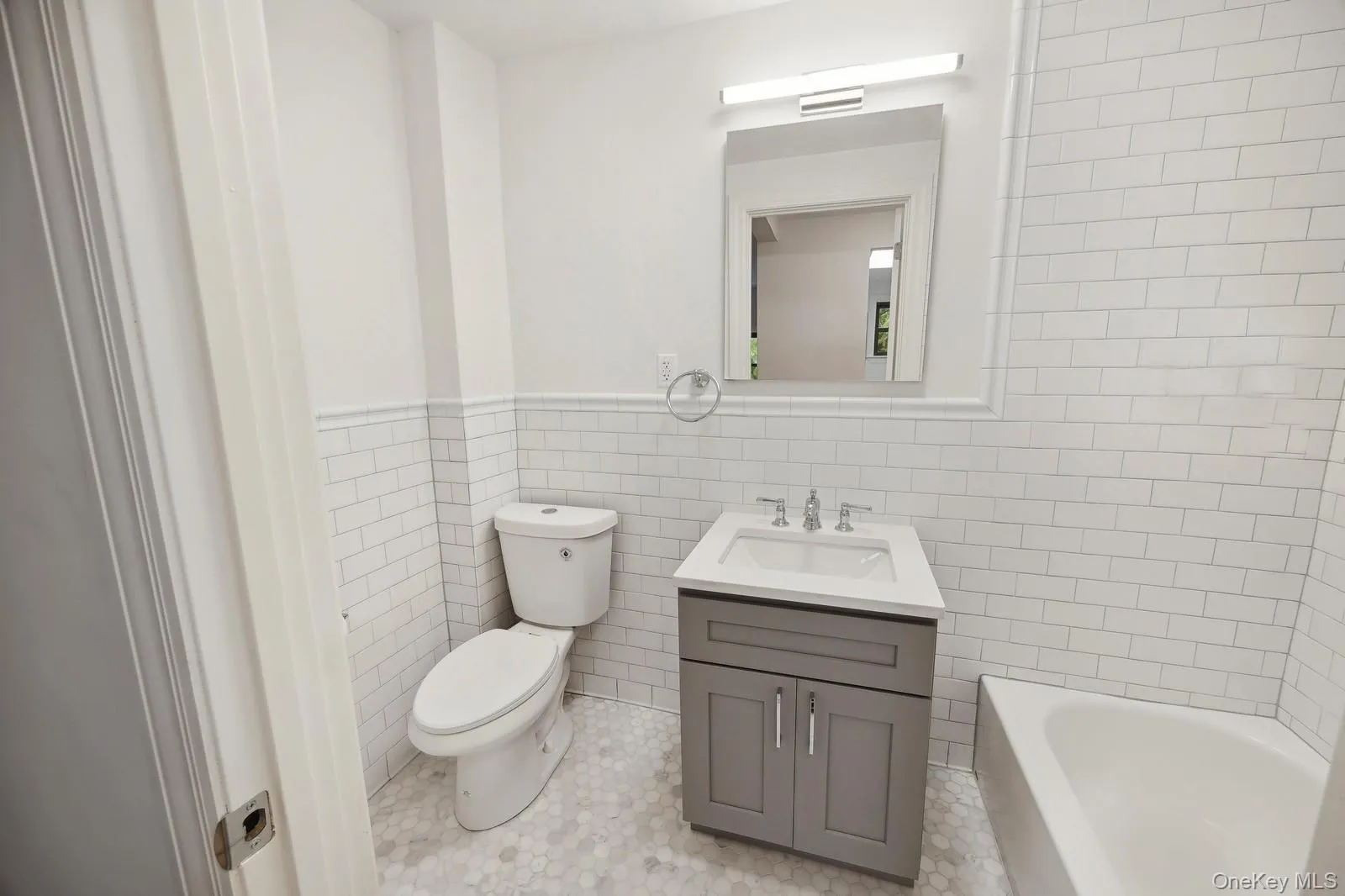 Bathroom featuring tile walls, vanity, light tile patterned floors, and a wainscoted wall Bathroom featuring tile walls, vanity, light tile patterned floors, and a wainscoted wall