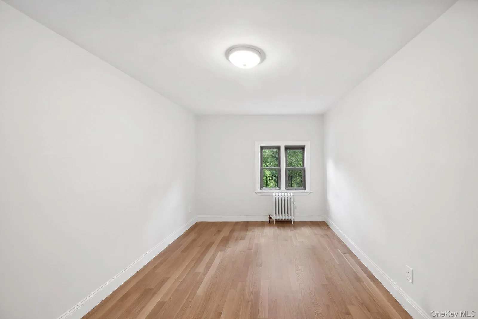 Empty room with light wood-style flooring and radiator Empty room with light wood-style flooring and radiator