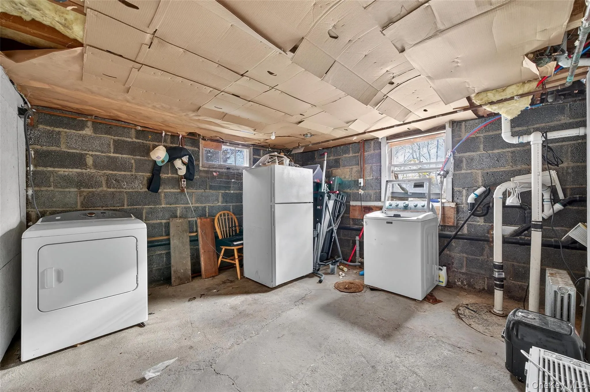 Below grade area featuring washer / clothes dryer, freestanding refrigerator, and healthy amount of natural light Below grade area featuring washer / clothes dryer, freestanding refrigerator, and healthy amount of natural light