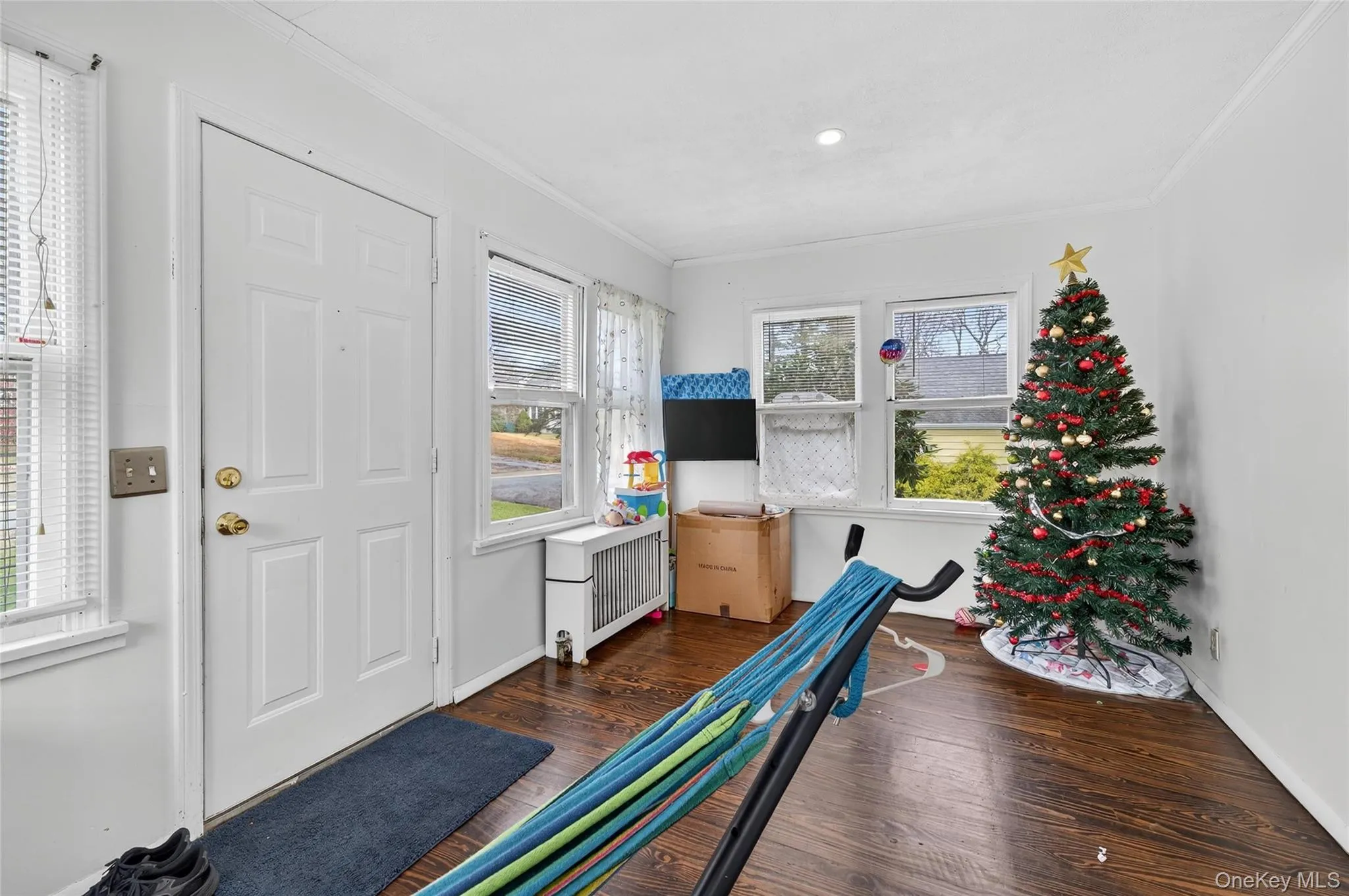 Workout area featuring dark wood-type flooring, radiator, and ornamental molding Workout area featuring dark wood-type flooring, radiator, and ornamental molding