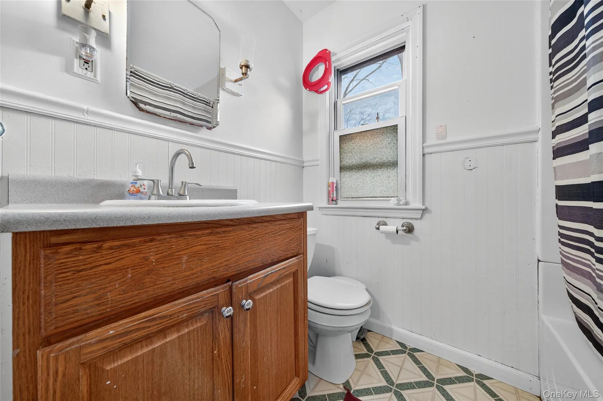 Bathroom with a wainscoted wall, vanity, and shower / bath combo Bathroom with a wainscoted wall, vanity, and shower / bath combo