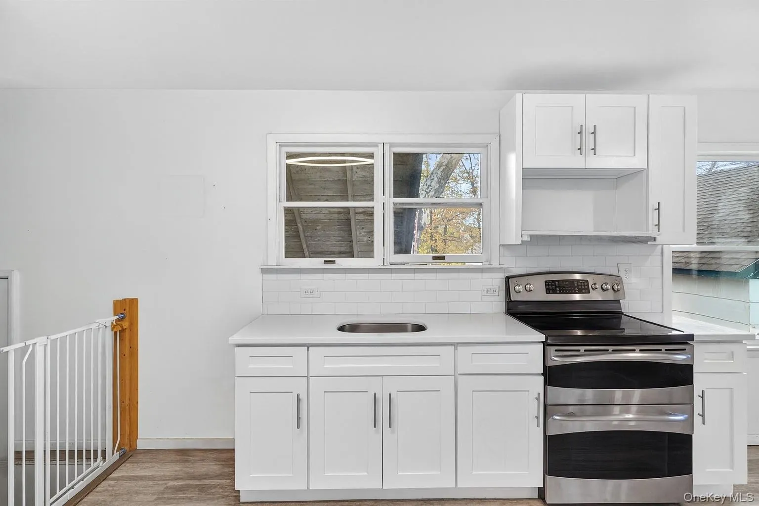 Kitchen with range with two ovens, white cabinetry, backsplash, and light stone countertops Kitchen with range with two ovens, white cabinetry, backsplash, and light stone countertops
