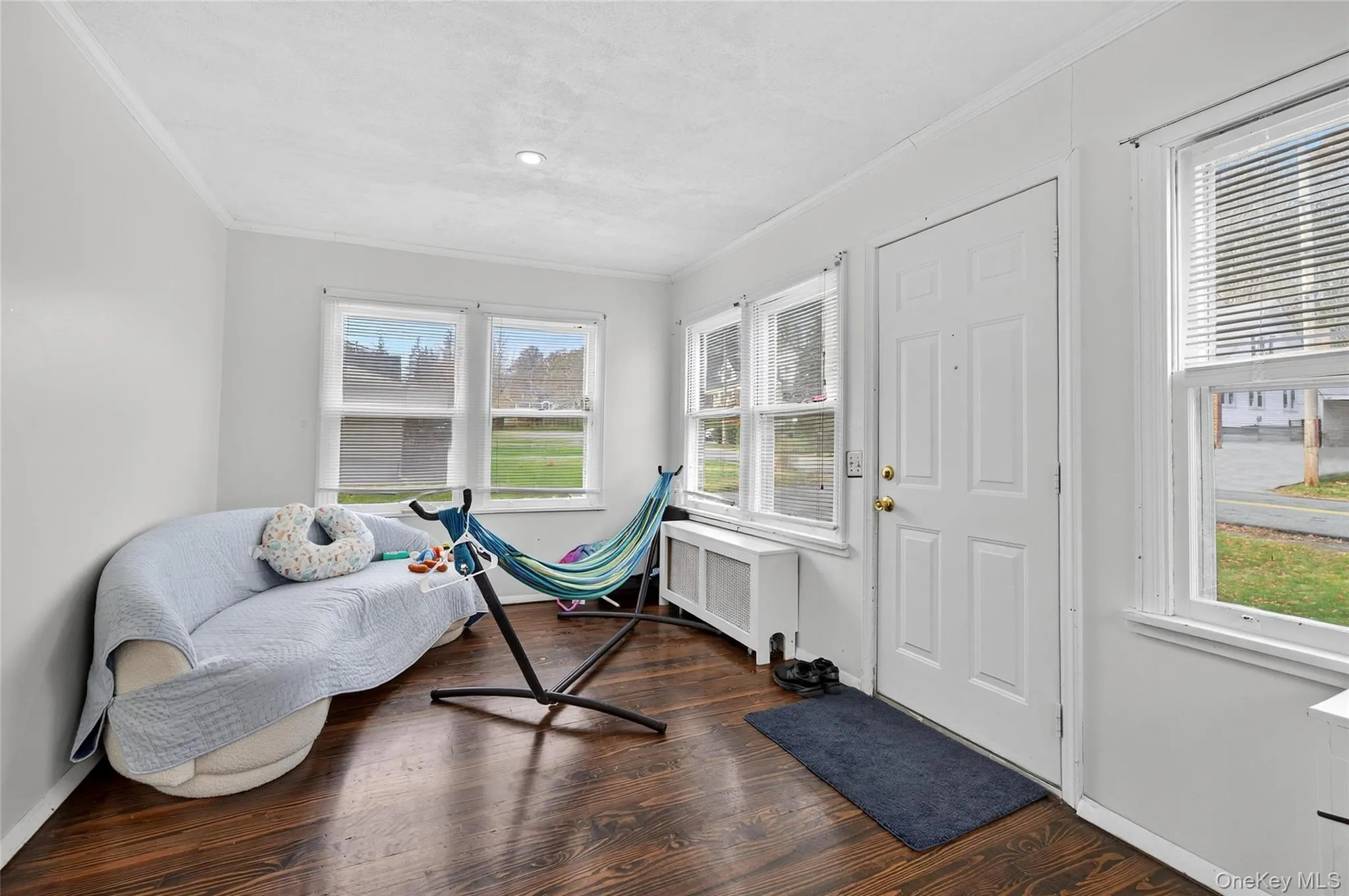 Living area with crown molding, radiator heating unit, and dark wood finished floors Living area with crown molding, radiator heating unit, and dark wood finished floors