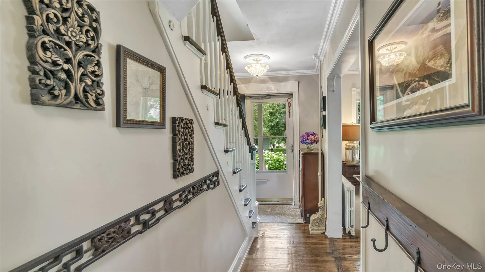 Hallway featuring dark wood-type flooring, ornamental molding, a chandelier, and radiator Hallway featuring dark wood-type flooring, ornamental molding, a chandelier, and radiator