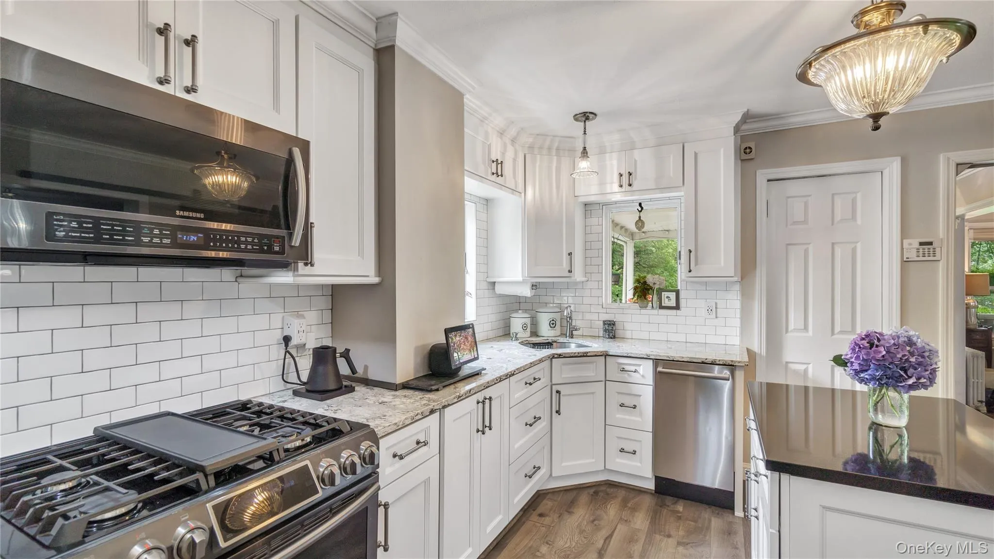 Kitchen featuring appliances with stainless steel finishes, white cabinets, dark stone counters, dark wood-style floors, and tasteful backsplash Kitchen featuring appliances with stainless steel finishes, white cabinets, dark stone counters, dark wood-style floors, and tasteful backsplash