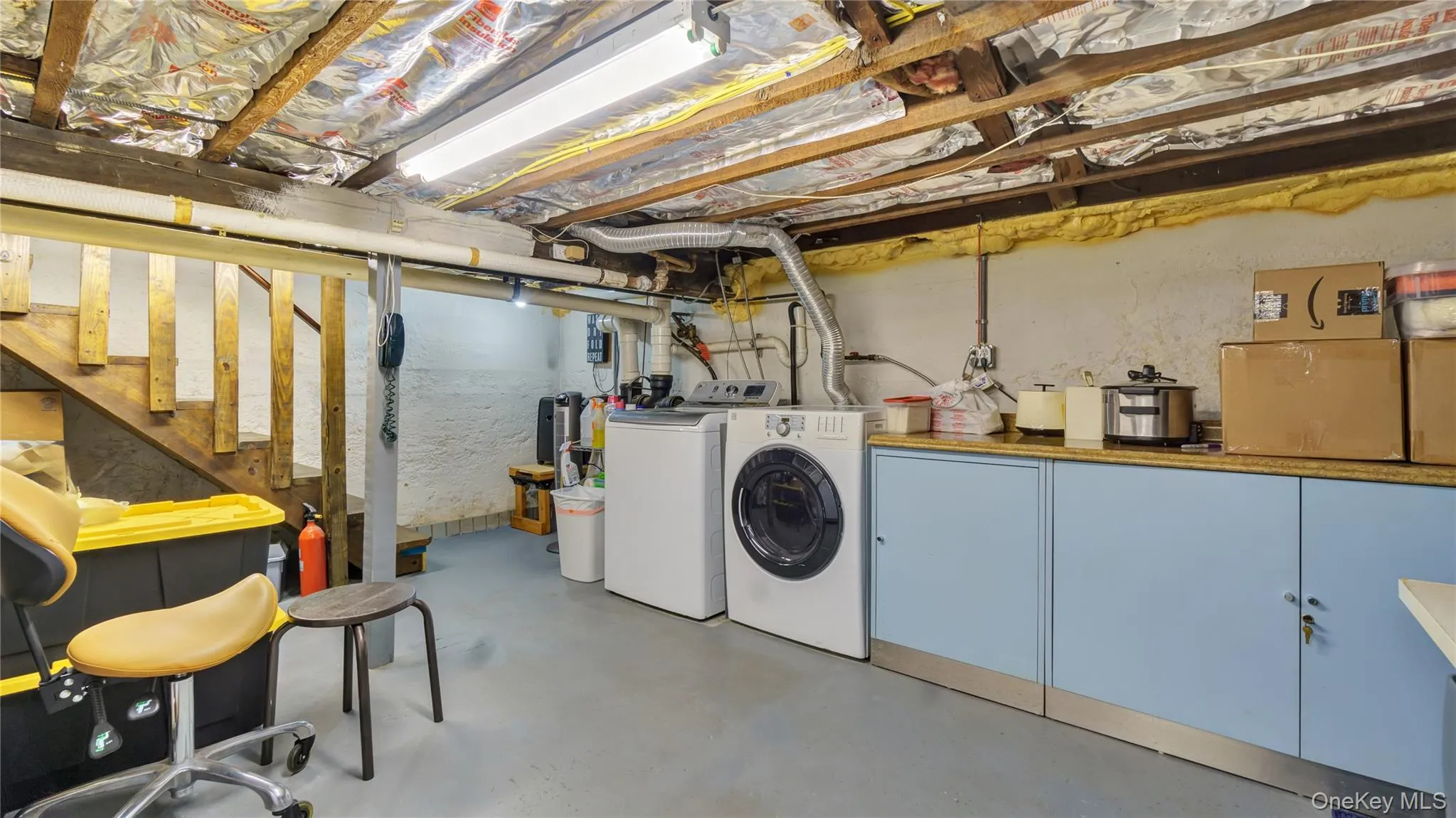 Unfinished below grade area featuring stairway and washer and clothes dryer Unfinished below grade area featuring stairway and washer and clothes dryer