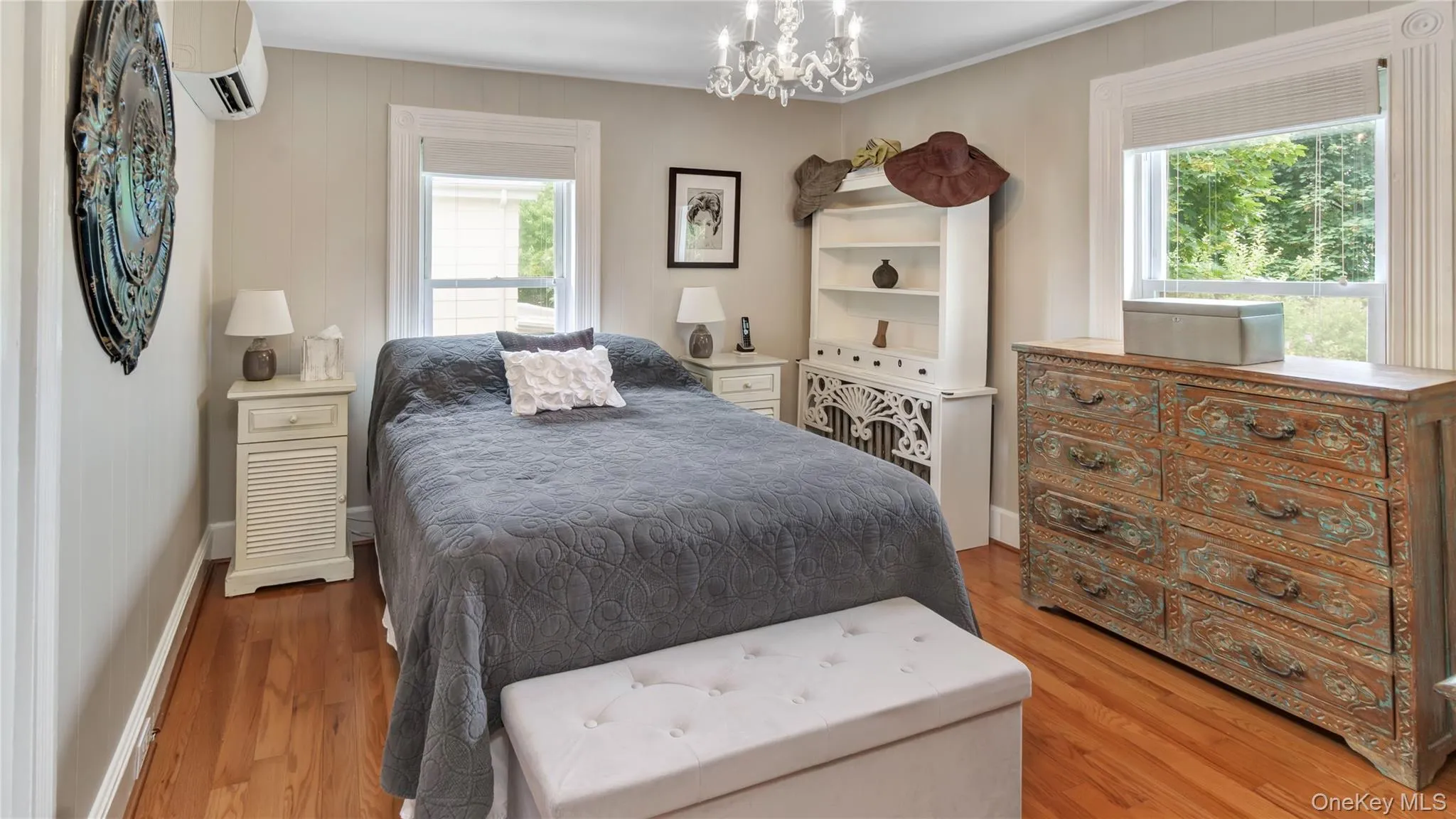 Bedroom featuring multiple windows, light wood-type flooring, an AC wall unit, a chandelier, and crown molding Bedroom featuring multiple windows, light wood-type flooring, an AC wall unit, a chandelier, and crown molding