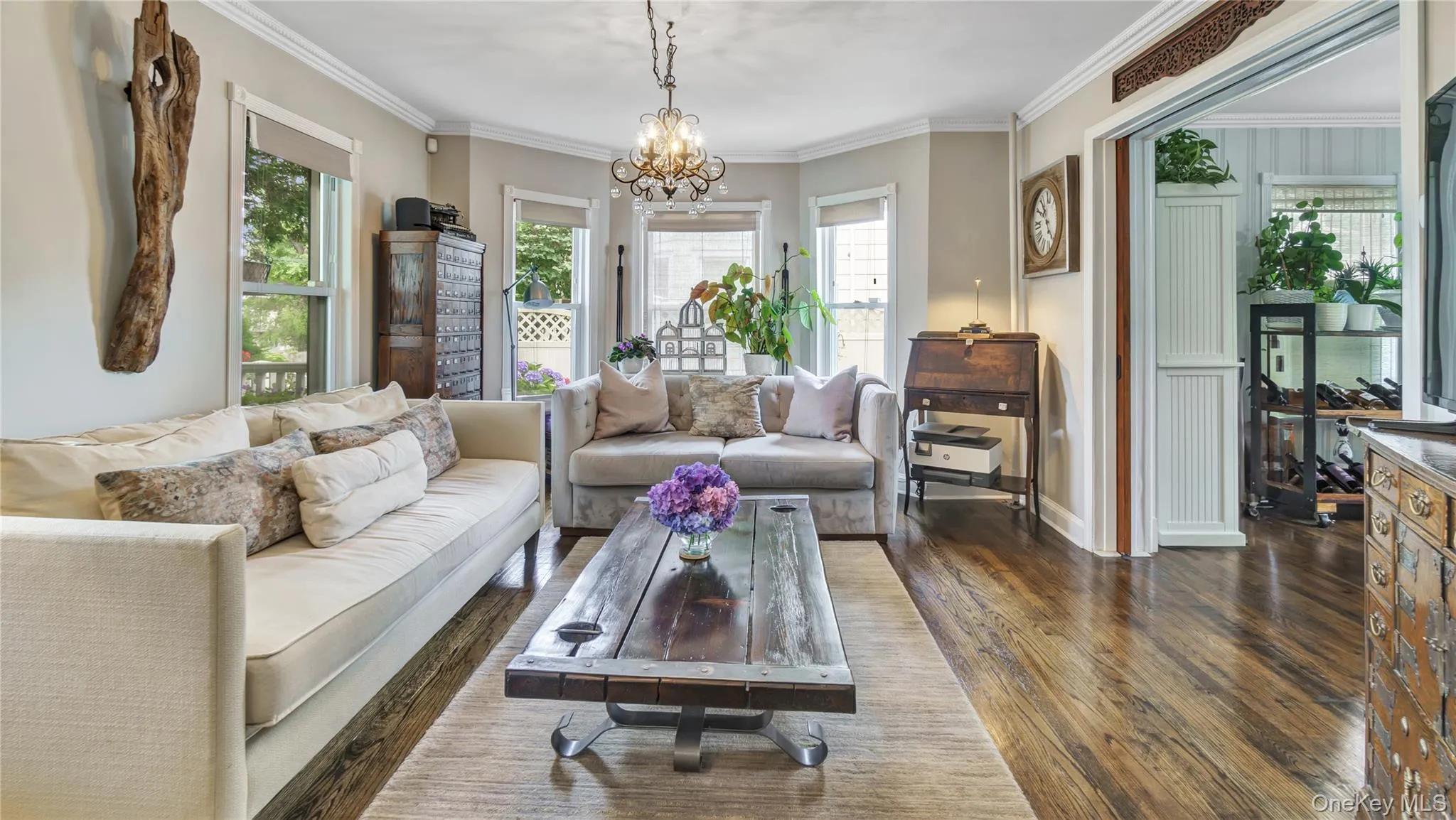 Living room featuring ornamental molding, dark wood-type flooring, and a chandelier Living room featuring ornamental molding, dark wood-type flooring, and a chandelier