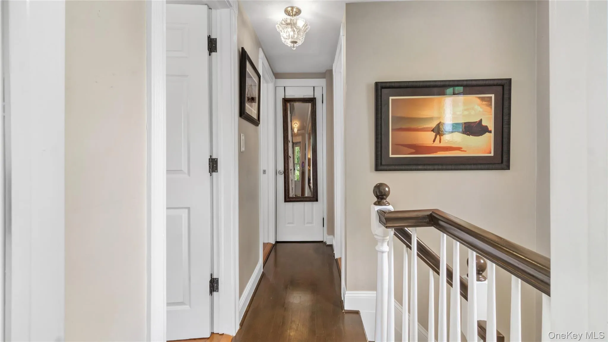 Corridor featuring dark wood-style flooring, an upstairs landing, and a chandelier Corridor featuring dark wood-style flooring, an upstairs landing, and a chandelier