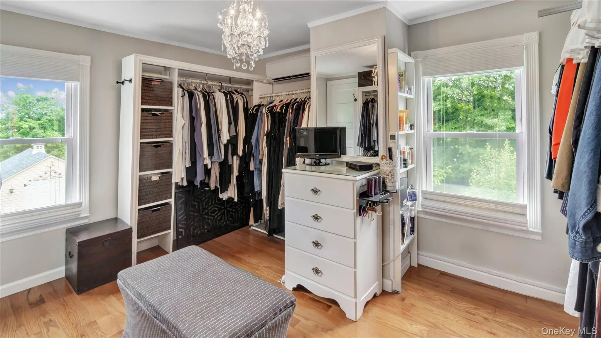 Spacious closet with light wood-type flooring, a chandelier, and an AC wall unit Spacious closet with light wood-type flooring, a chandelier, and an AC wall unit