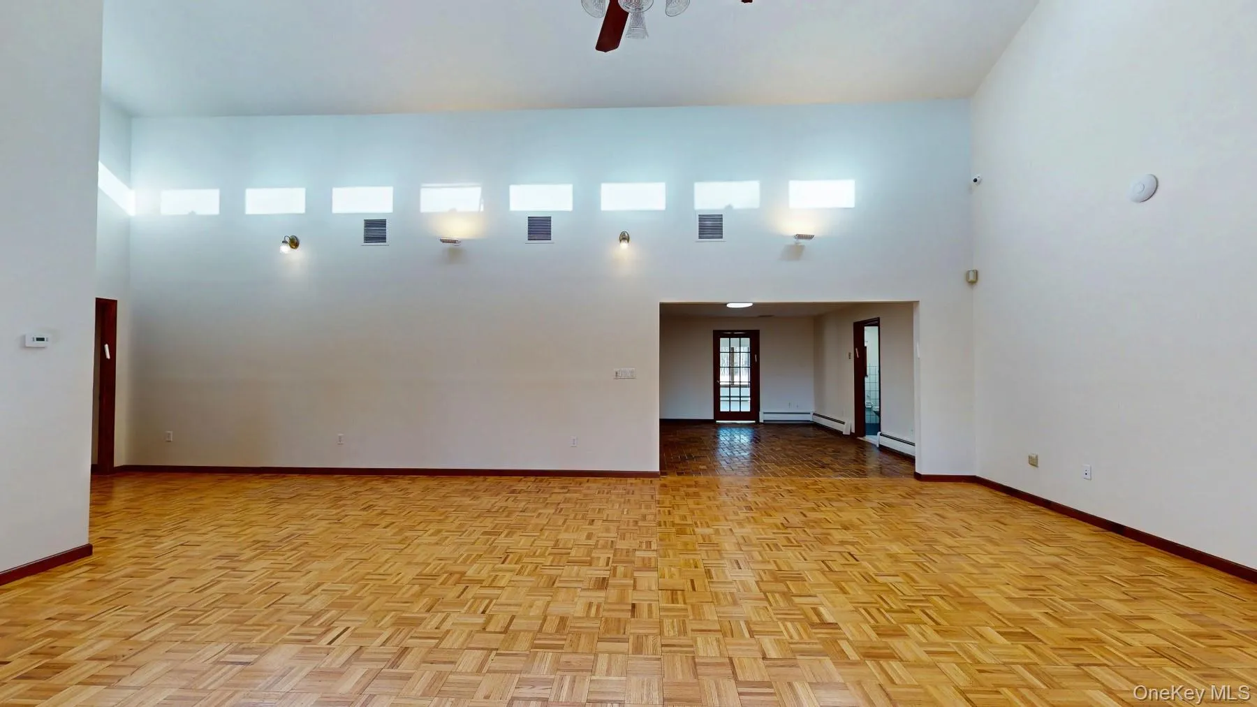 Unfurnished room featuring visible vents, baseboards, a towering ceiling, and a ceiling fan Unfurnished room featuring visible vents, baseboards, a towering ceiling, and a ceiling fan
