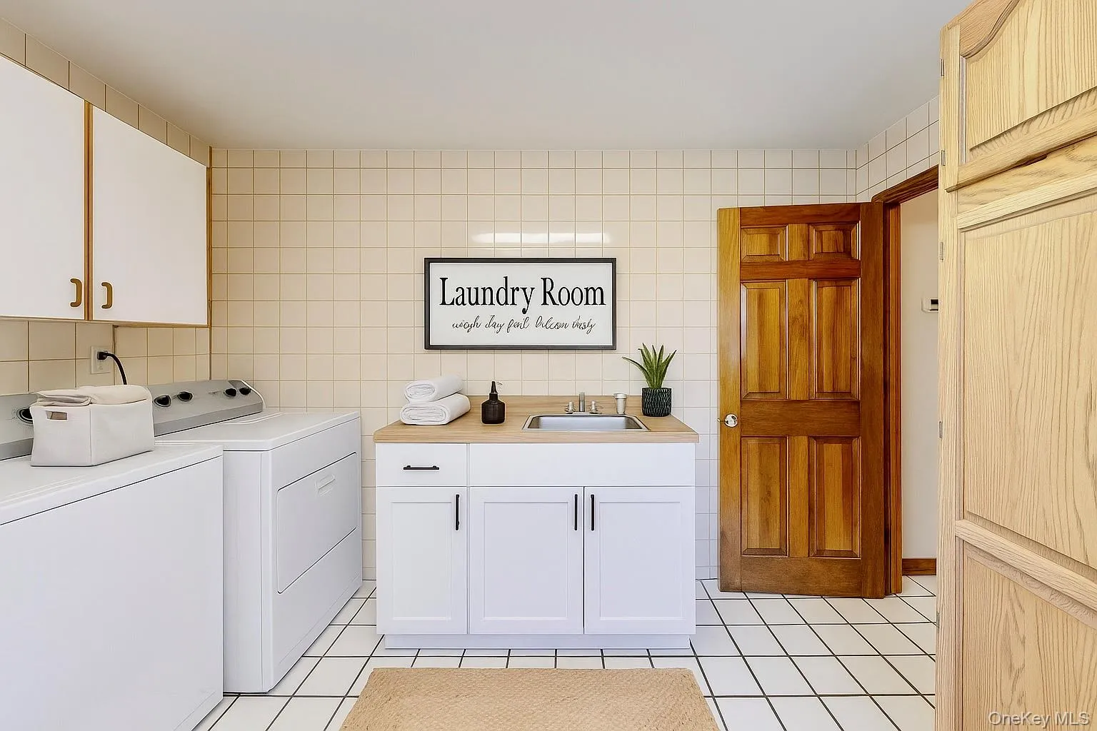 Washroom featuring cabinet space, tile walls, light tile patterned flooring, and washer and dryer(Virtually staged) Washroom featuring cabinet space, tile walls, light tile patterned flooring, and washer and dryer(Virtually staged)