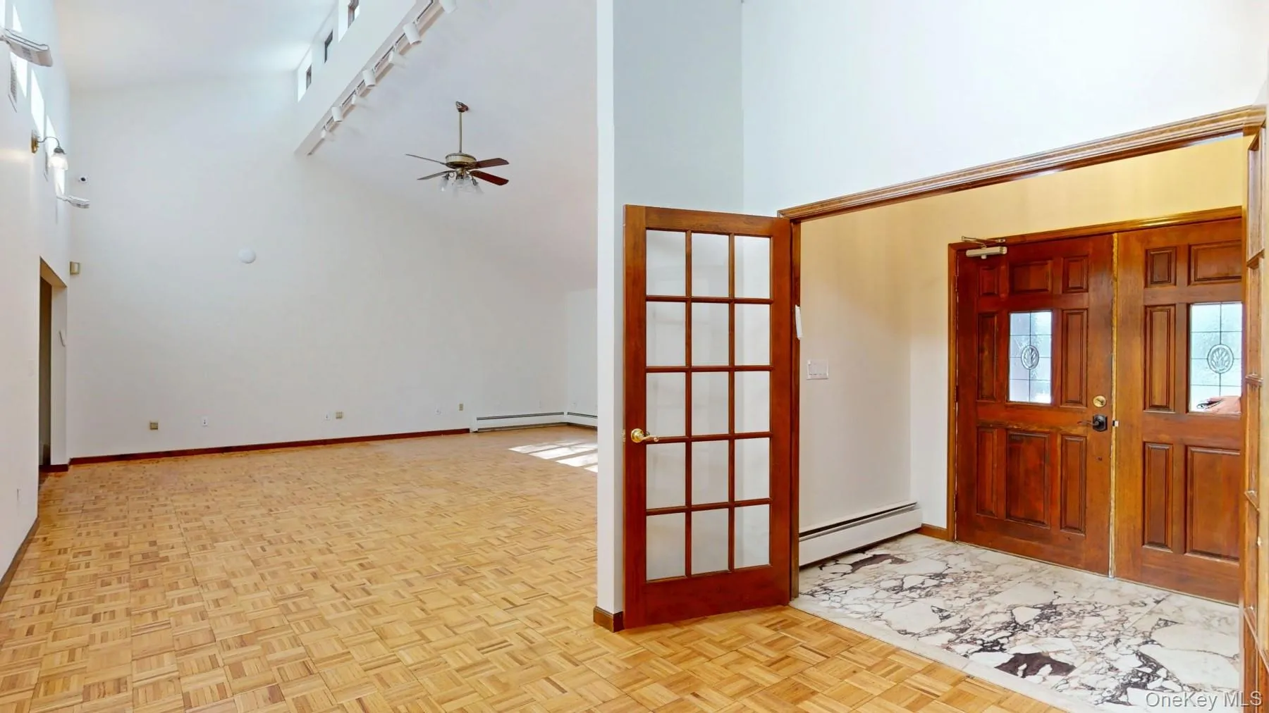 Foyer with rail lighting, high vaulted ceiling, ceiling fan, and a baseboard radiator Foyer with rail lighting, high vaulted ceiling, ceiling fan, and a baseboard radiator