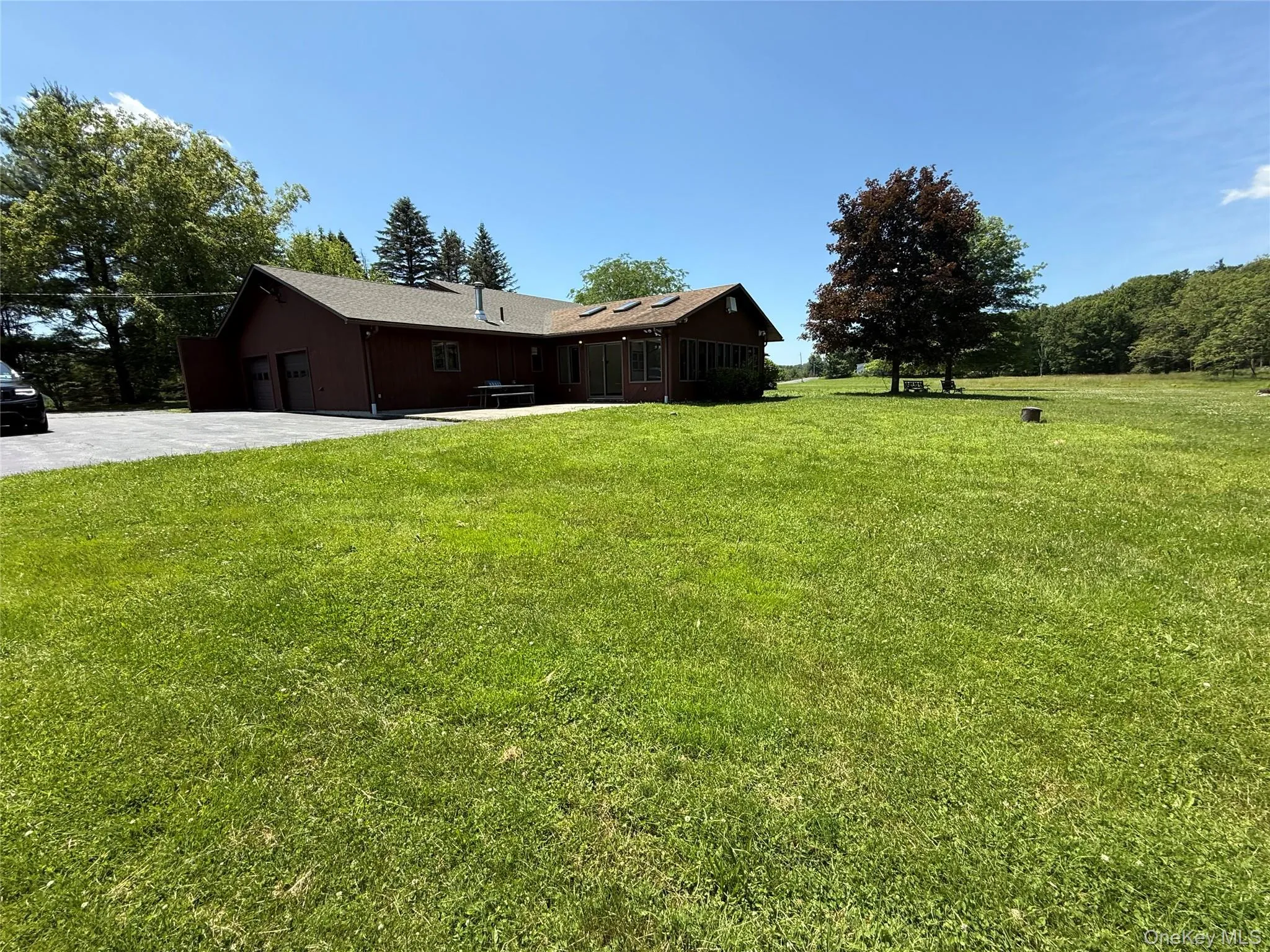 View of green lawn featuring driveway and a garage View of green lawn featuring driveway and a garage