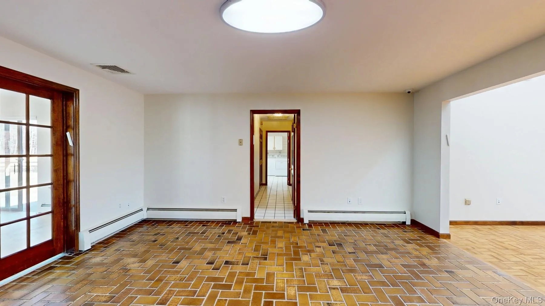 Unfurnished room featuring brick floor, a baseboard radiator, baseboards, and visible vents Unfurnished room featuring brick floor, a baseboard radiator, baseboards, and visible vents