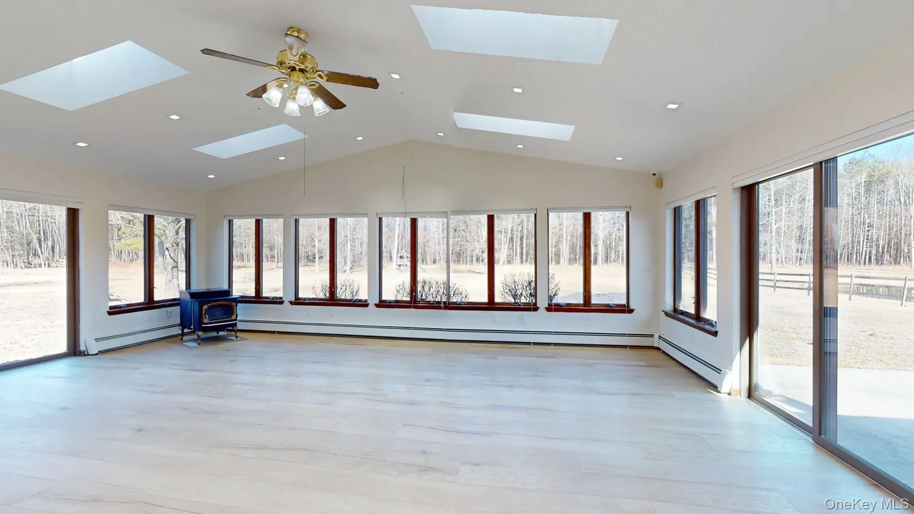 Unfurnished sunroom with a skylight, baseboard heating, and a wood stove Unfurnished sunroom with a skylight, baseboard heating, and a wood stove