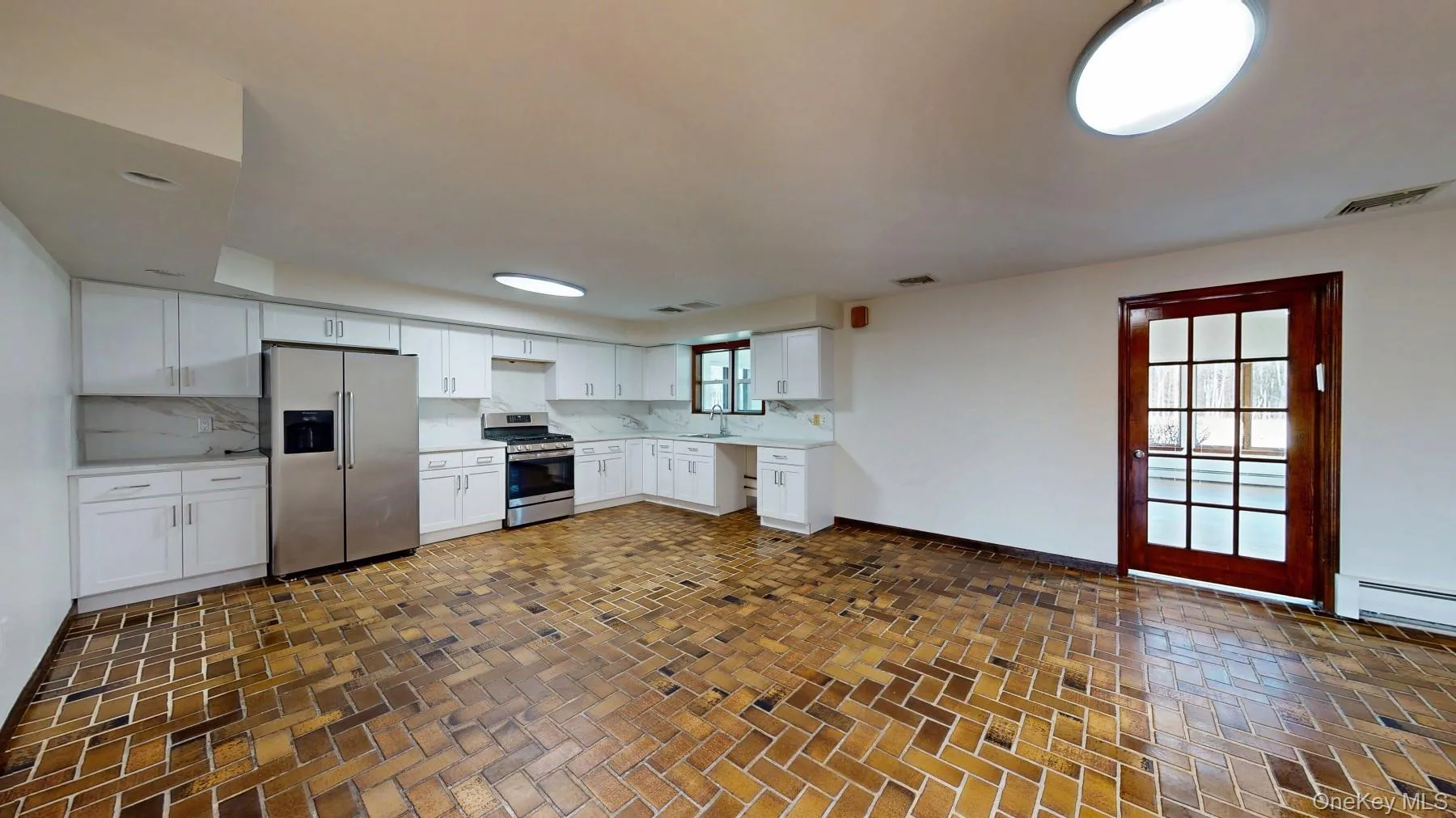 Kitchen featuring a sink, stainless steel appliances, decorative backsplash, and light countertops Kitchen featuring a sink, stainless steel appliances, decorative backsplash, and light countertops