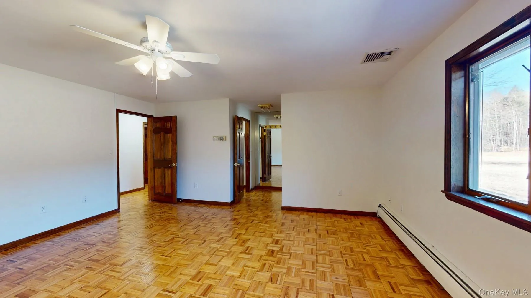 Empty room featuring visible vents, a ceiling fan, a baseboard heating unit, and baseboards Empty room featuring visible vents, a ceiling fan, a baseboard heating unit, and baseboards