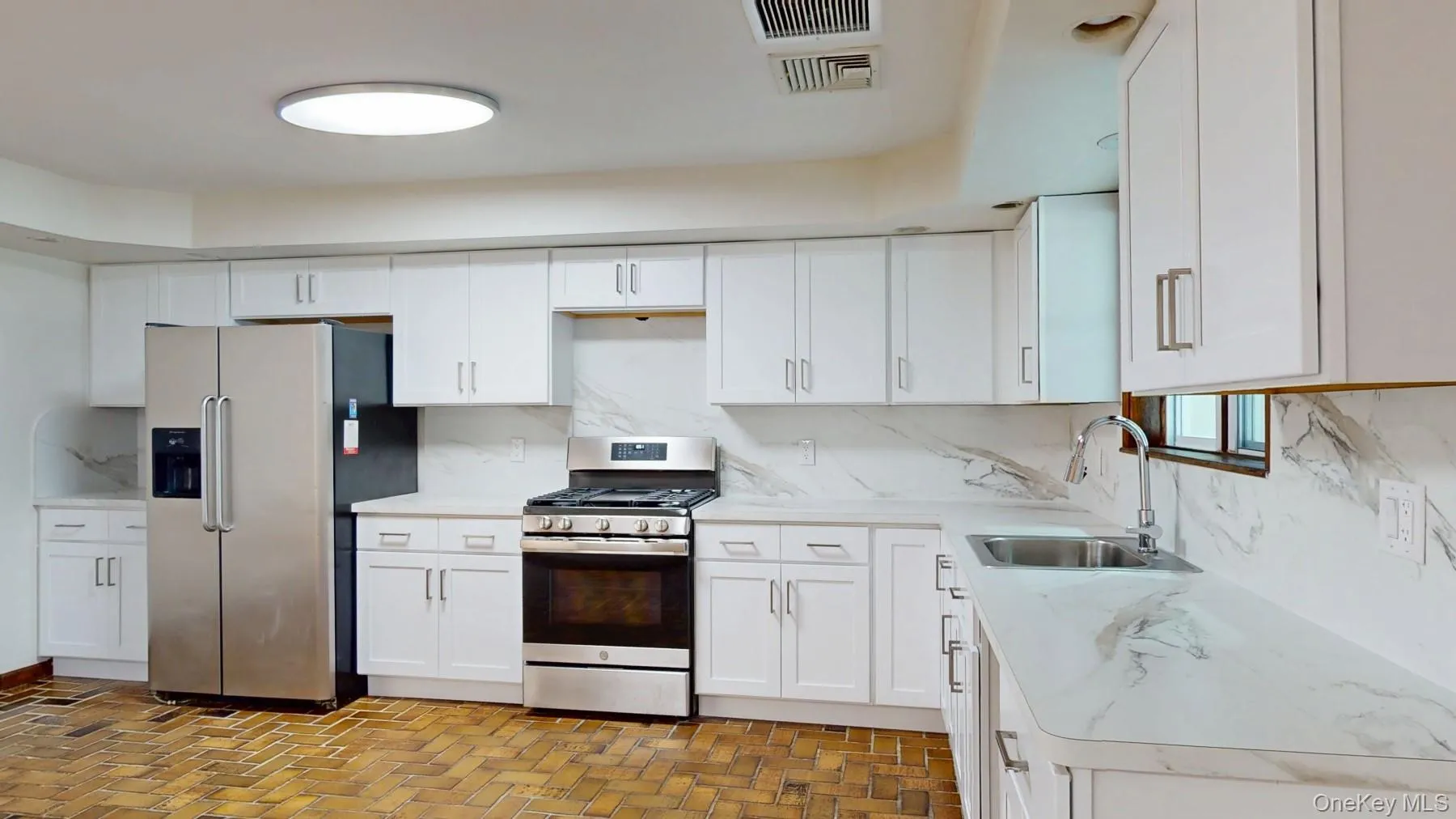 Kitchen featuring a sink, white cabinets, backsplash, and stainless steel appliances Kitchen featuring a sink, white cabinets, backsplash, and stainless steel appliances