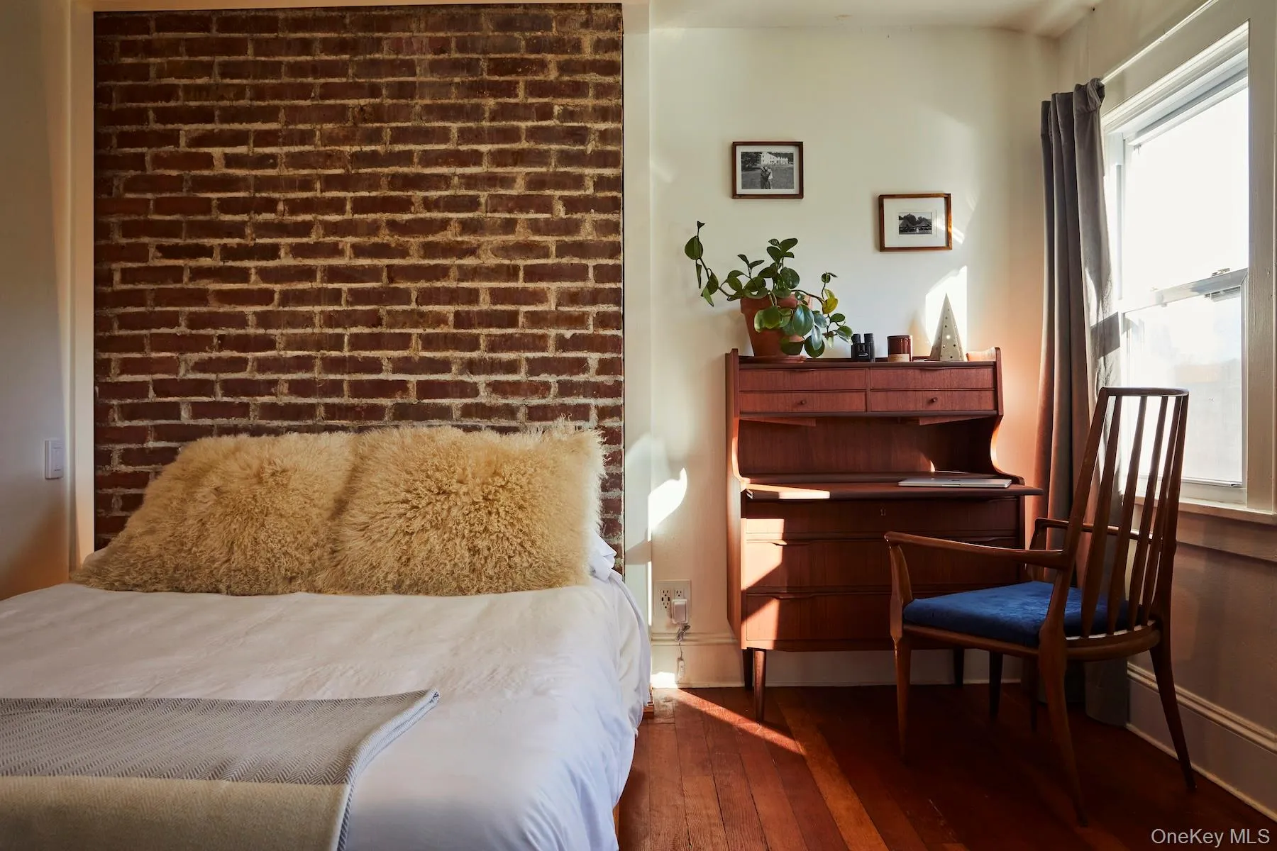 Bedroom with dark wood-style floors and brick wall Bedroom with dark wood-style floors and brick wall