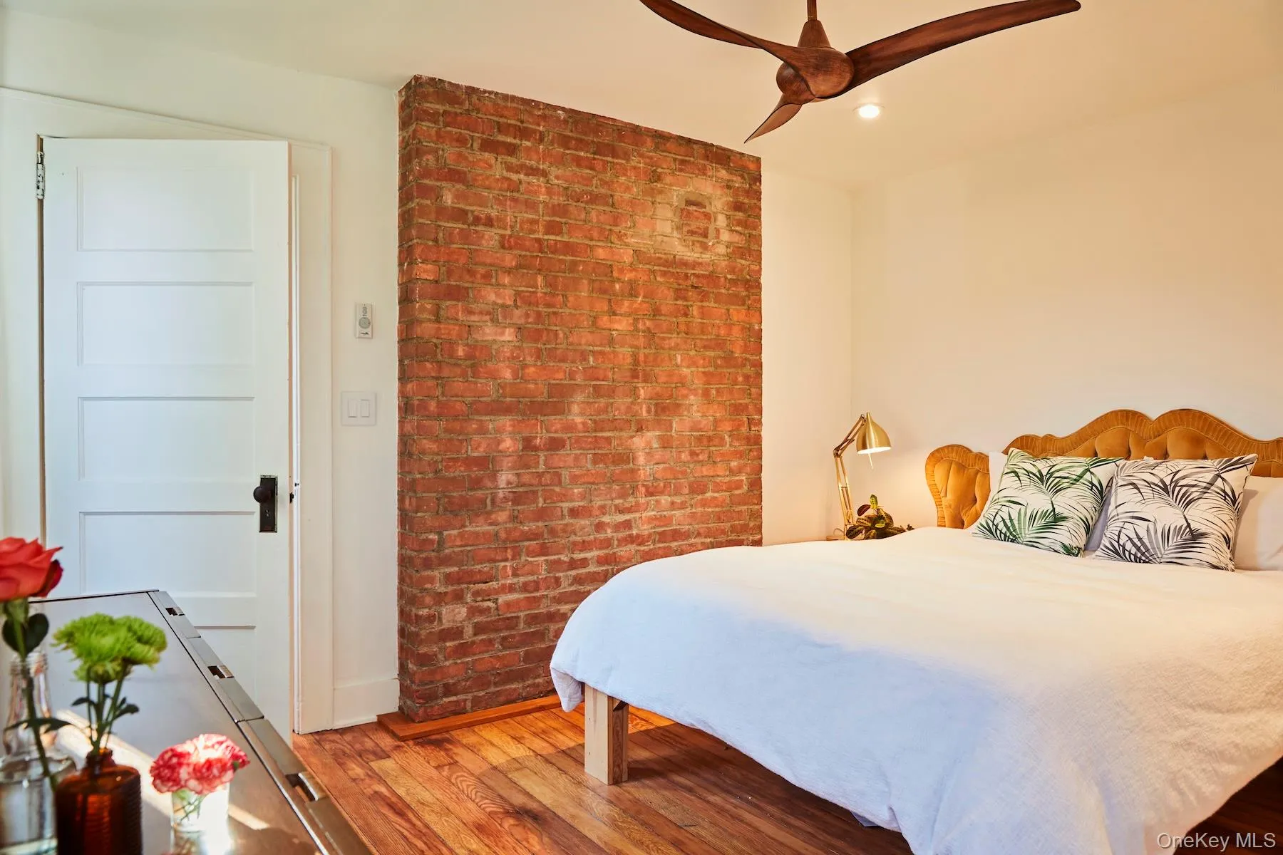 Bedroom with wood finished floors, a ceiling fan, recessed lighting, and brick wall Bedroom with wood finished floors, a ceiling fan, recessed lighting, and brick wall