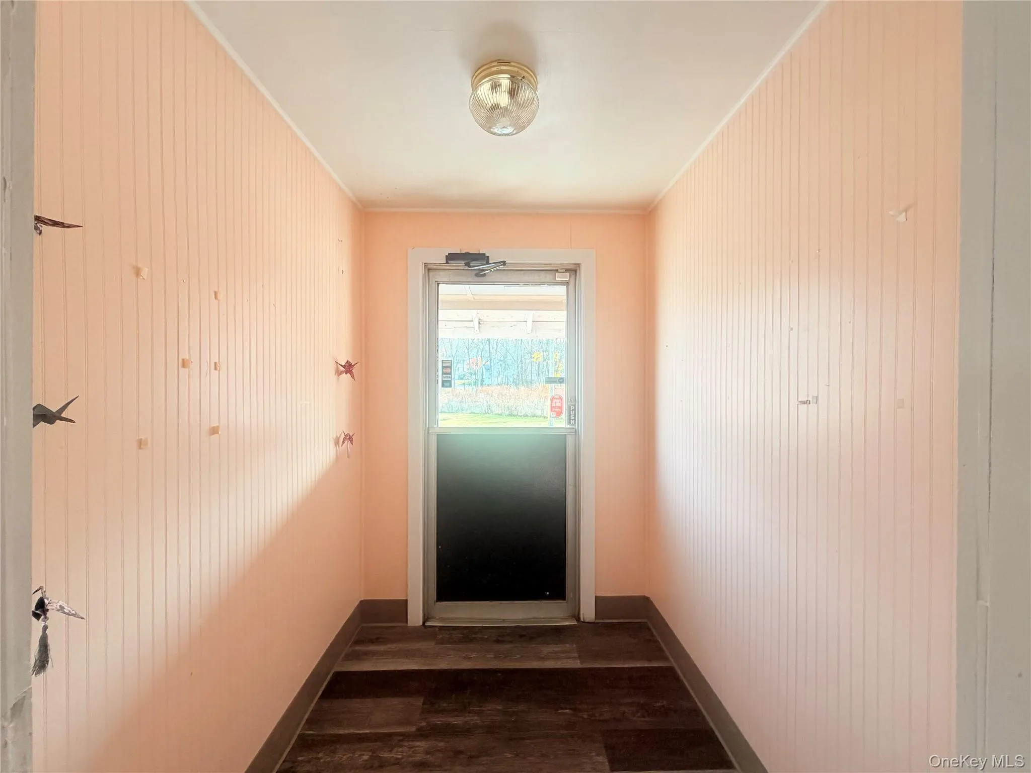 Doorway featuring wood finished floors, crown molding, and wood walls Doorway featuring wood finished floors, crown molding, and wood walls