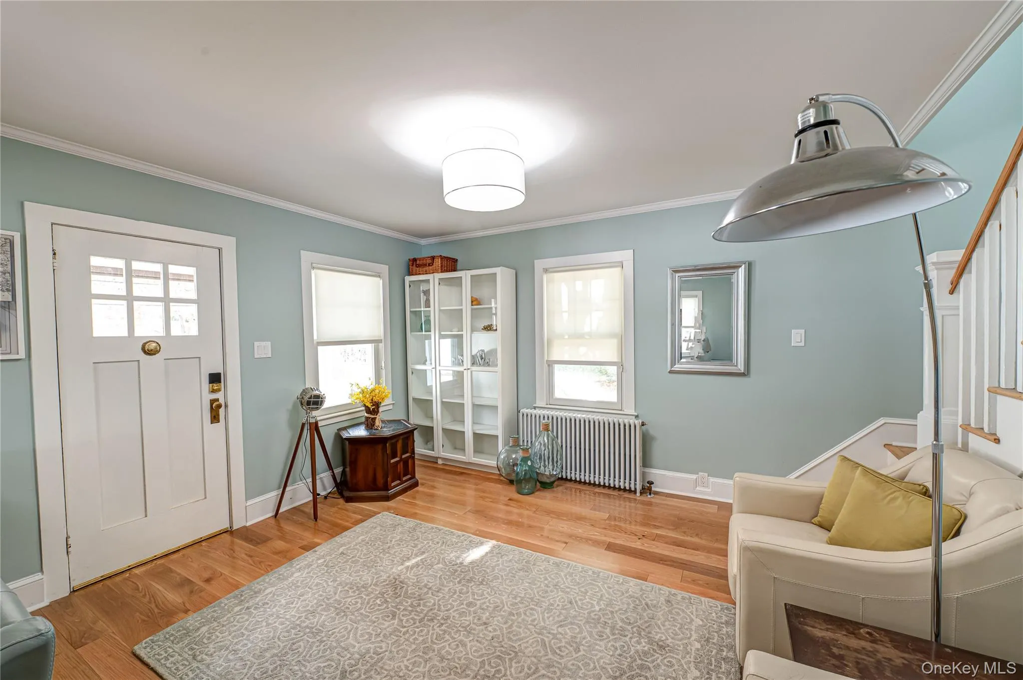 Entrance foyer with ornamental molding, radiator heating unit, light wood-type flooring, and stairway Entrance foyer with ornamental molding, radiator heating unit, light wood-type flooring, and stairway