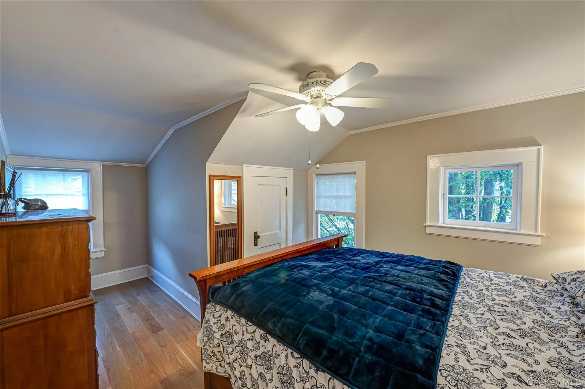 Bedroom with ornamental molding, vaulted ceiling, wood finished floors, and a ceiling fan Bedroom with ornamental molding, vaulted ceiling, wood finished floors, and a ceiling fan