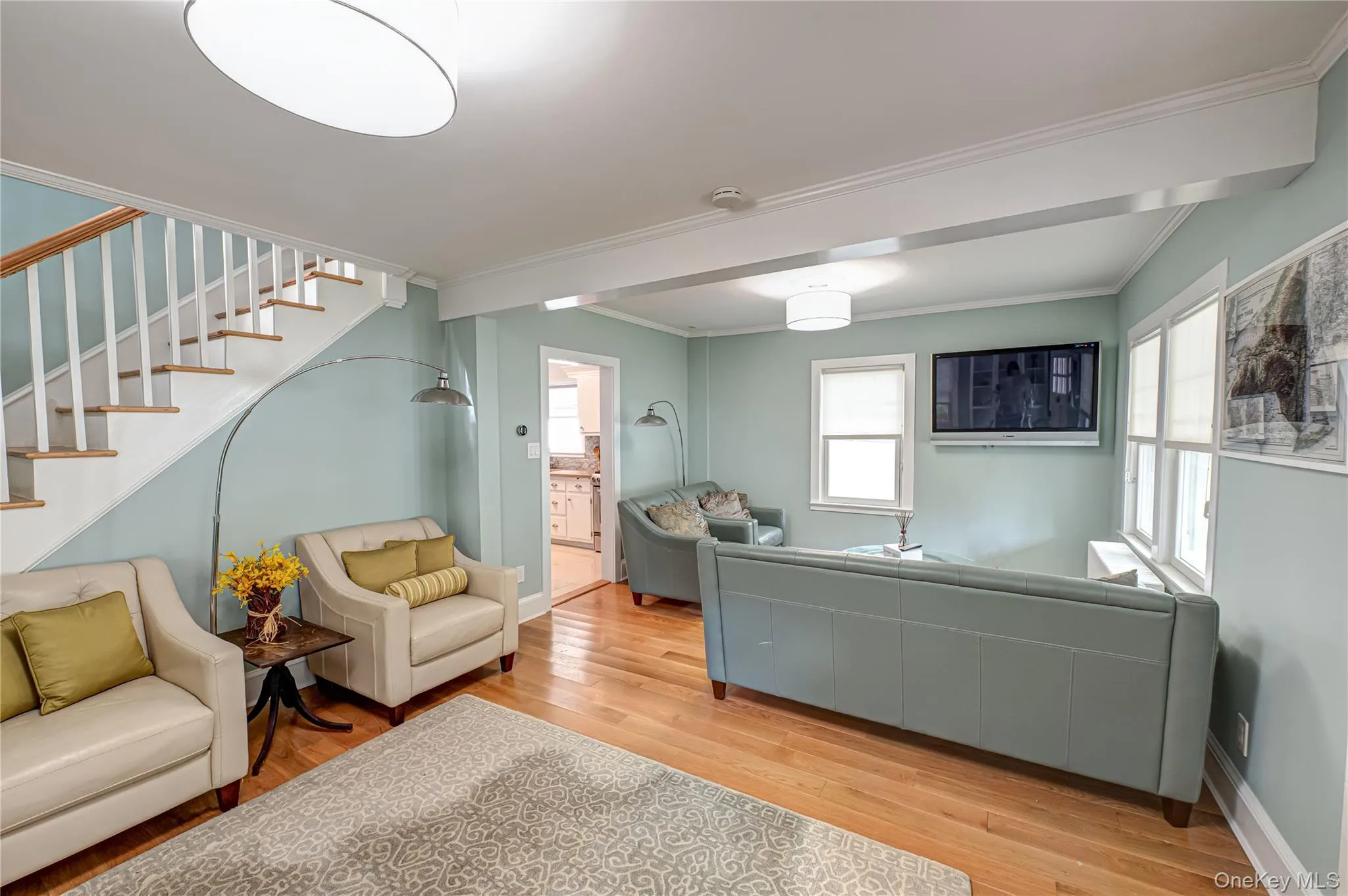 Living room with stairway, crown molding, and light wood finished floors Living room with stairway, crown molding, and light wood finished floors