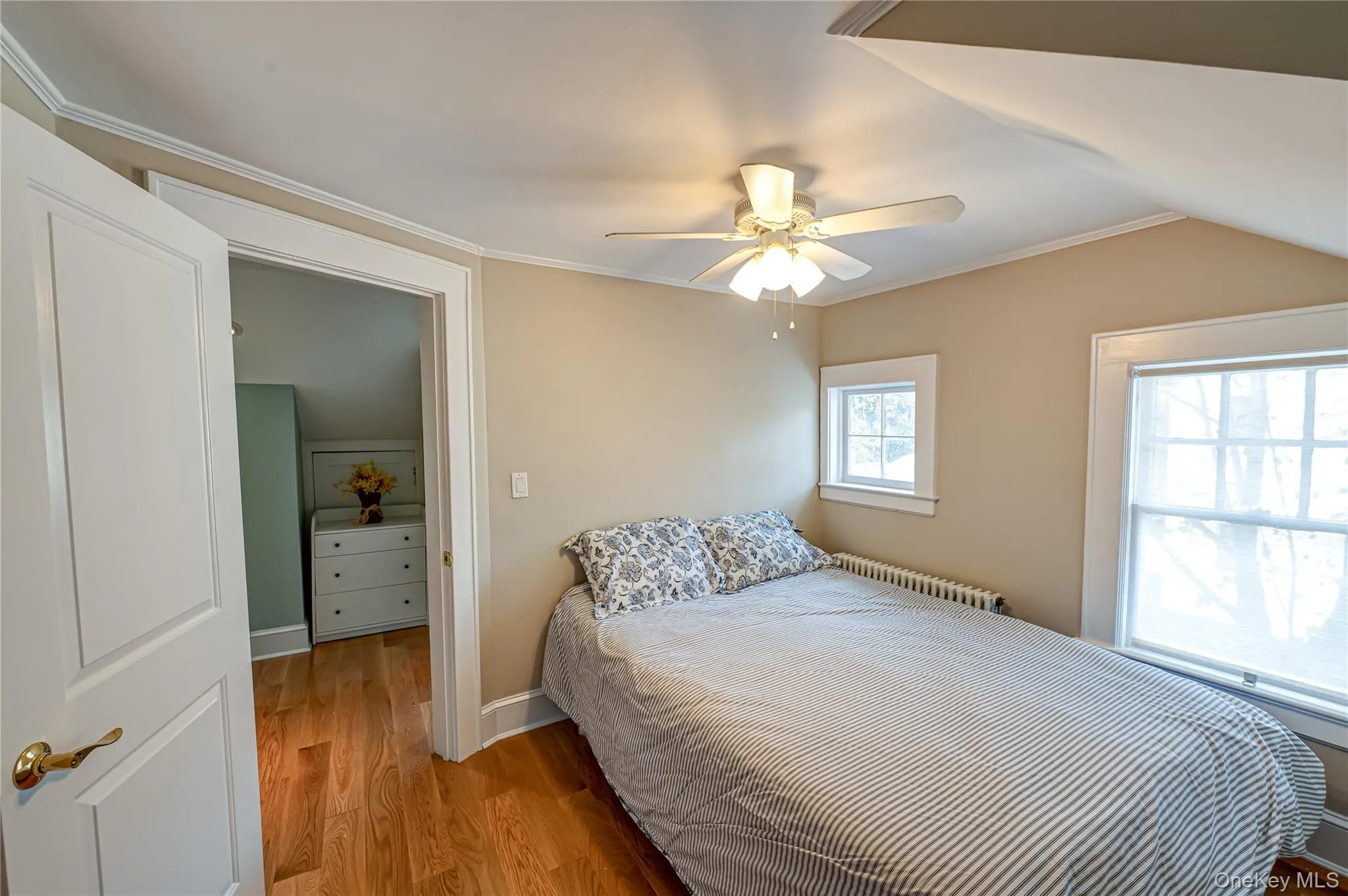 Bedroom with crown molding, wood finished floors, radiator heating unit, and a ceiling fan Bedroom with crown molding, wood finished floors, radiator heating unit, and a ceiling fan