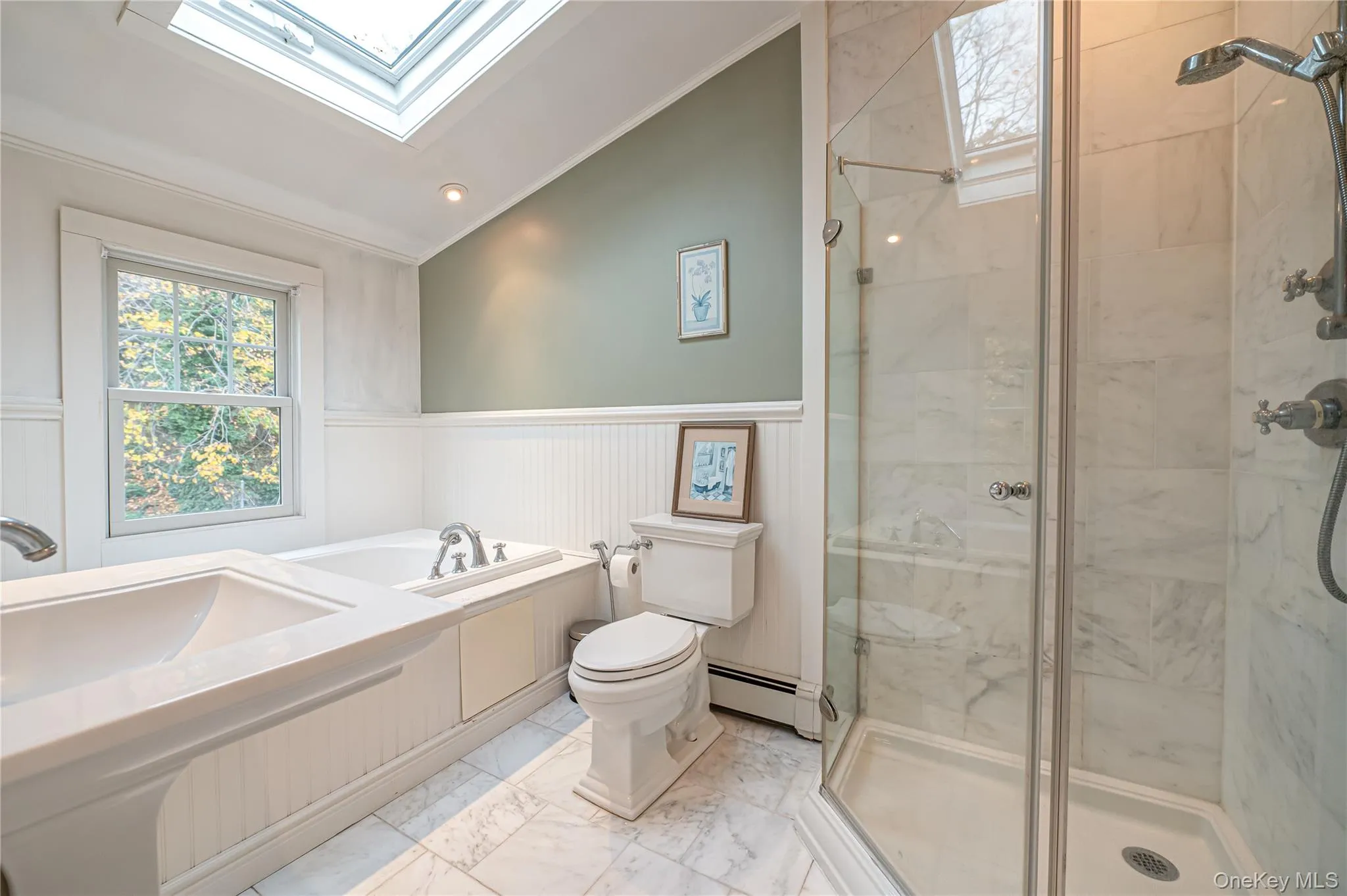Bathroom with a marble finish shower, a skylight, lofted ceiling, wainscoting, and a baseboard radiator Bathroom with a marble finish shower, a skylight, lofted ceiling, wainscoting, and a baseboard radiator