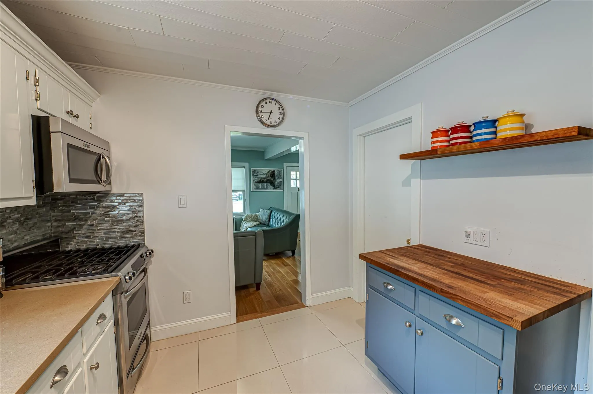 Kitchen with butcher block countertops, appliances with stainless steel finishes, ornamental molding, blue cabinets, and backsplash Kitchen with butcher block countertops, appliances with stainless steel finishes, ornamental molding, blue cabinets, and backsplash