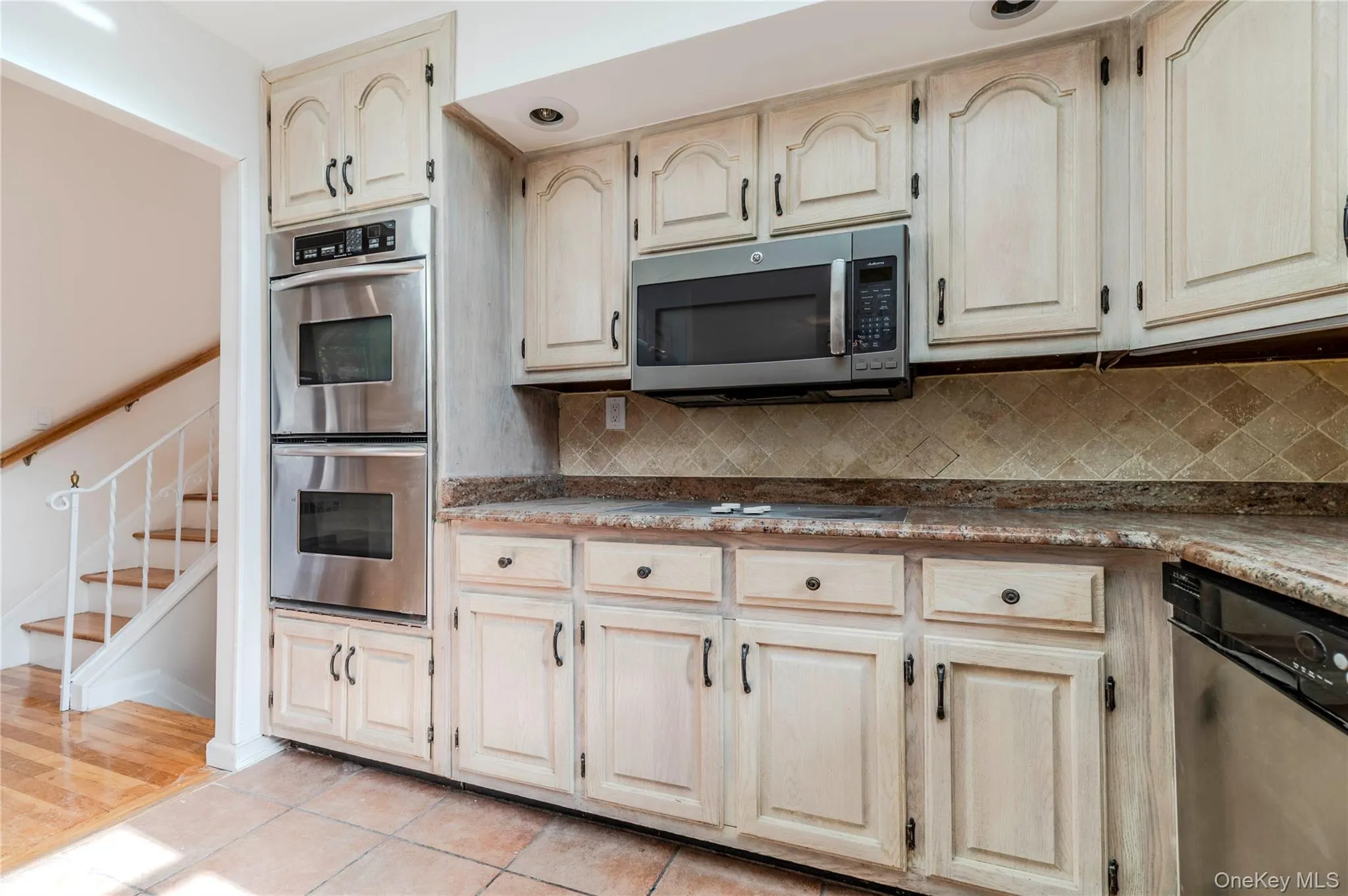 Kitchen with stainless steel appliances, decorative backsplash, light tile patterned floors, and light brown cabinets Kitchen with stainless steel appliances, decorative backsplash, light tile patterned floors, and light brown cabinets