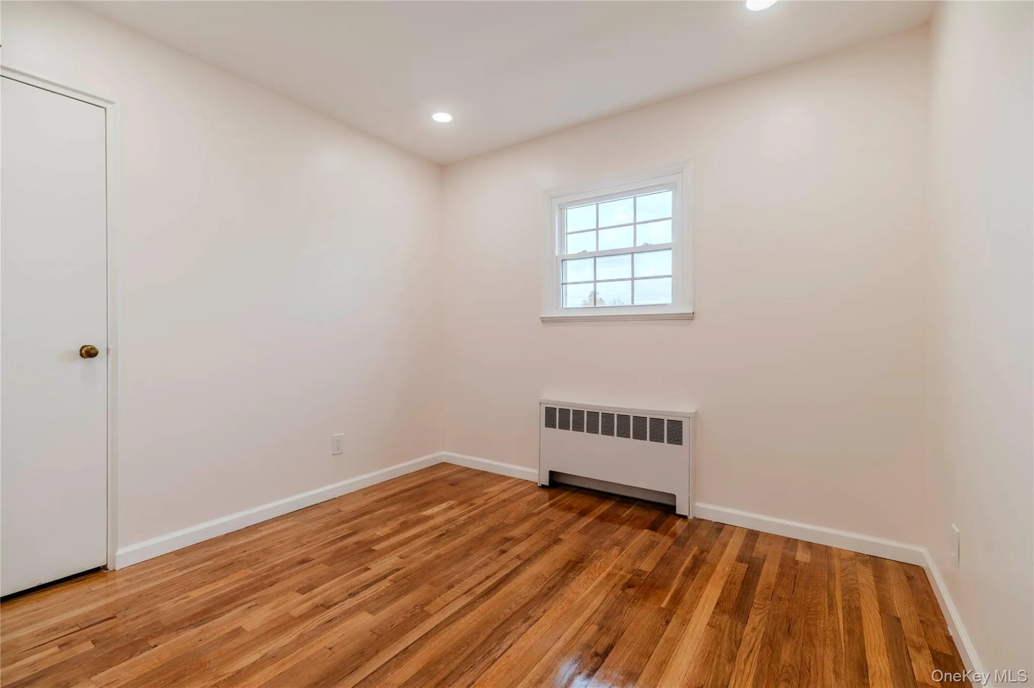 Unfurnished room featuring radiator heating unit, wood finished floors, and recessed lighting Unfurnished room featuring radiator heating unit, wood finished floors, and recessed lighting