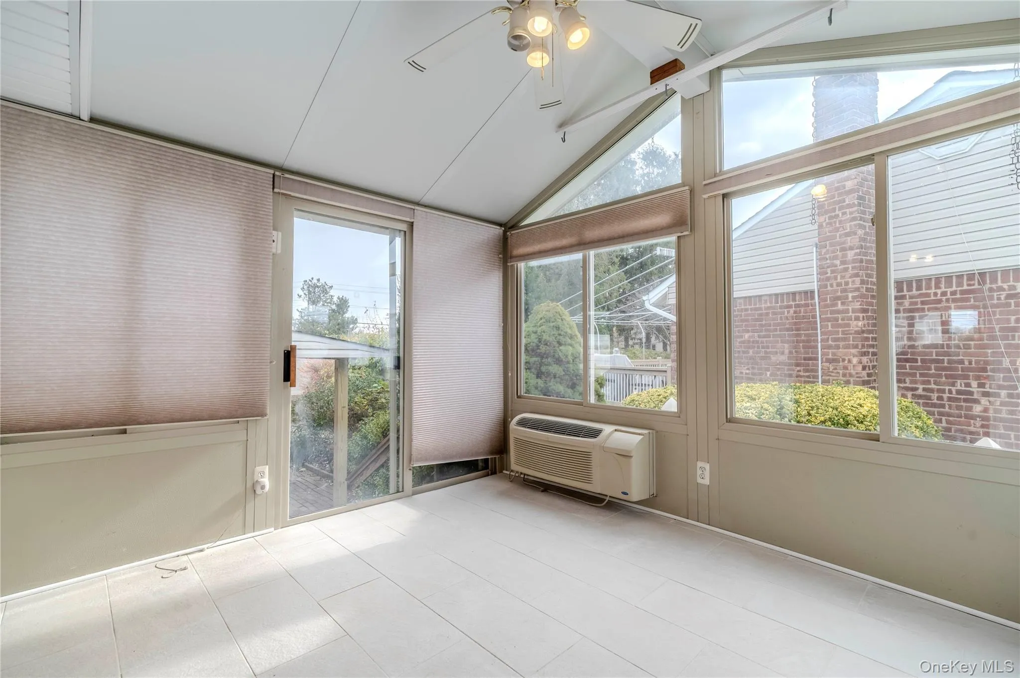 Unfurnished sunroom with vaulted ceiling, healthy amount of natural light, and an AC wall unit Unfurnished sunroom with vaulted ceiling, healthy amount of natural light, and an AC wall unit