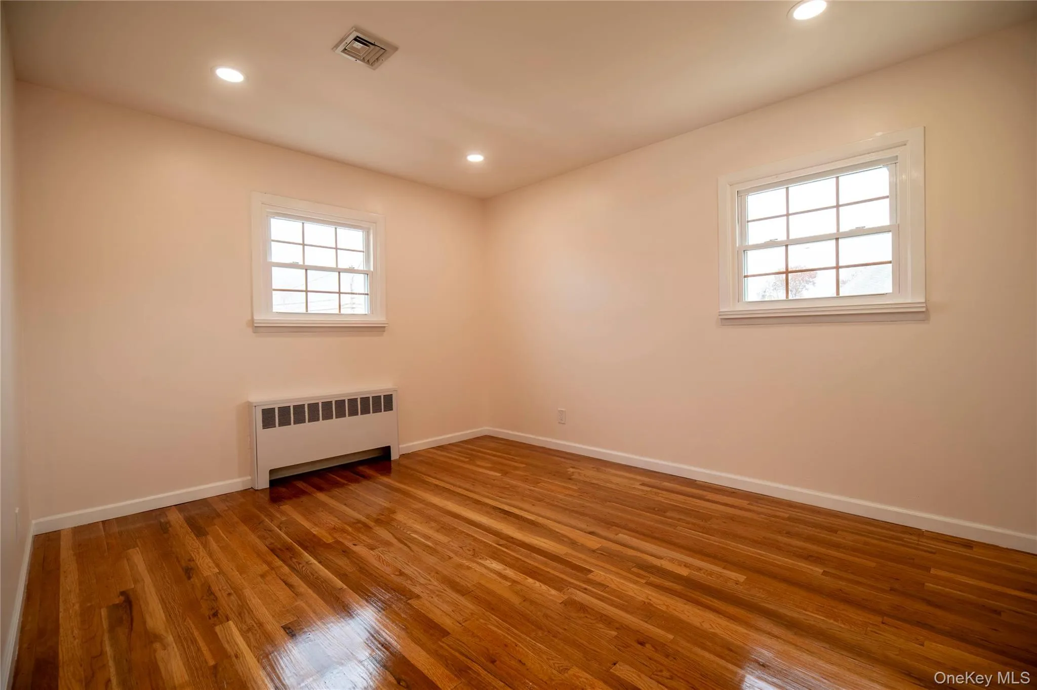 Unfurnished room featuring radiator heating unit, recessed lighting, and light wood-style flooring Unfurnished room featuring radiator heating unit, recessed lighting, and light wood-style flooring