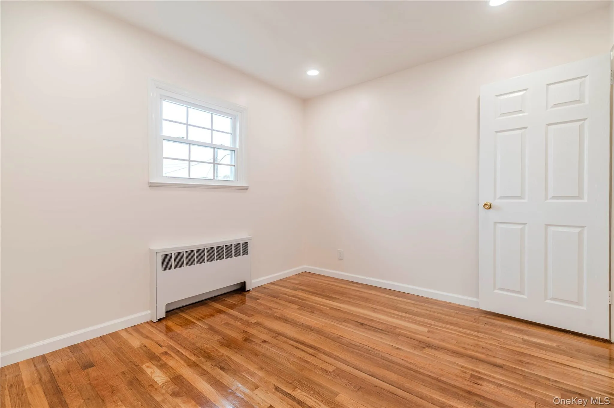 Spare room featuring radiator heating unit, light wood-style flooring, and recessed lighting Spare room featuring radiator heating unit, light wood-style flooring, and recessed lighting