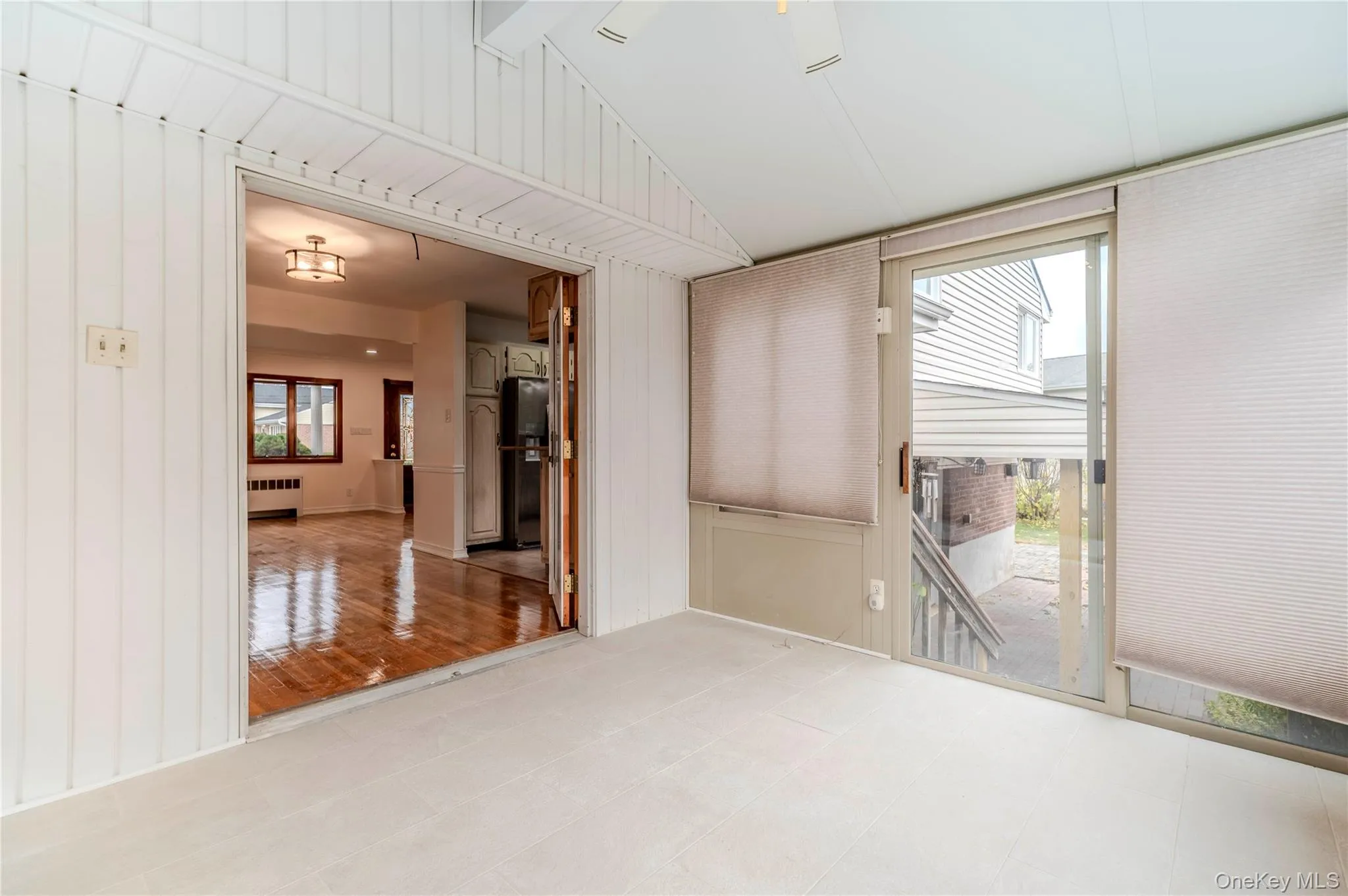Empty room featuring radiator heating unit, vaulted ceiling, and wooden walls Empty room featuring radiator heating unit, vaulted ceiling, and wooden walls