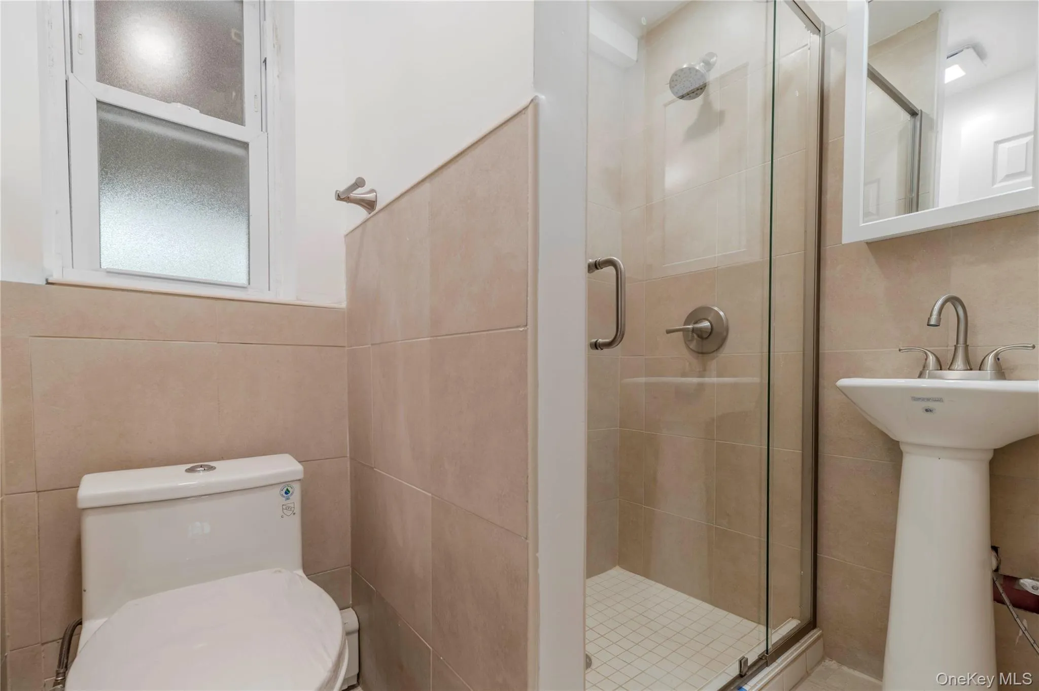 Full bathroom featuring a shower stall and tile walls Full bathroom featuring a shower stall and tile walls
