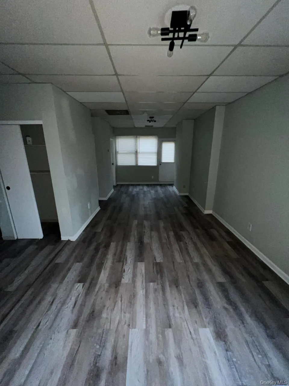 Spare room with a drop ceiling and dark wood-style flooring Spare room with a drop ceiling and dark wood-style flooring