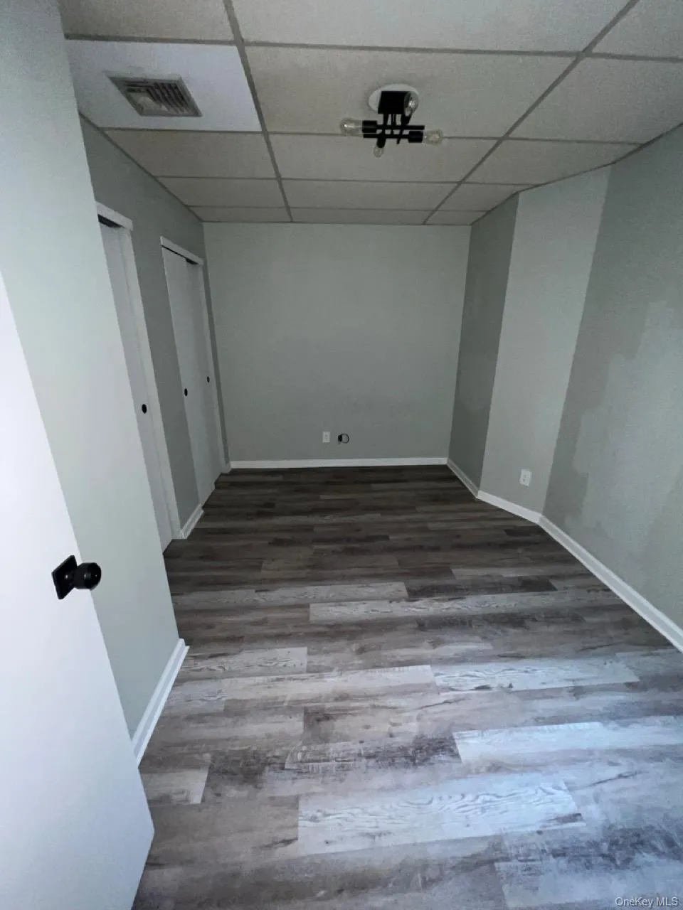 Unfurnished room with dark wood-type flooring and a paneled ceiling Unfurnished room with dark wood-type flooring and a paneled ceiling