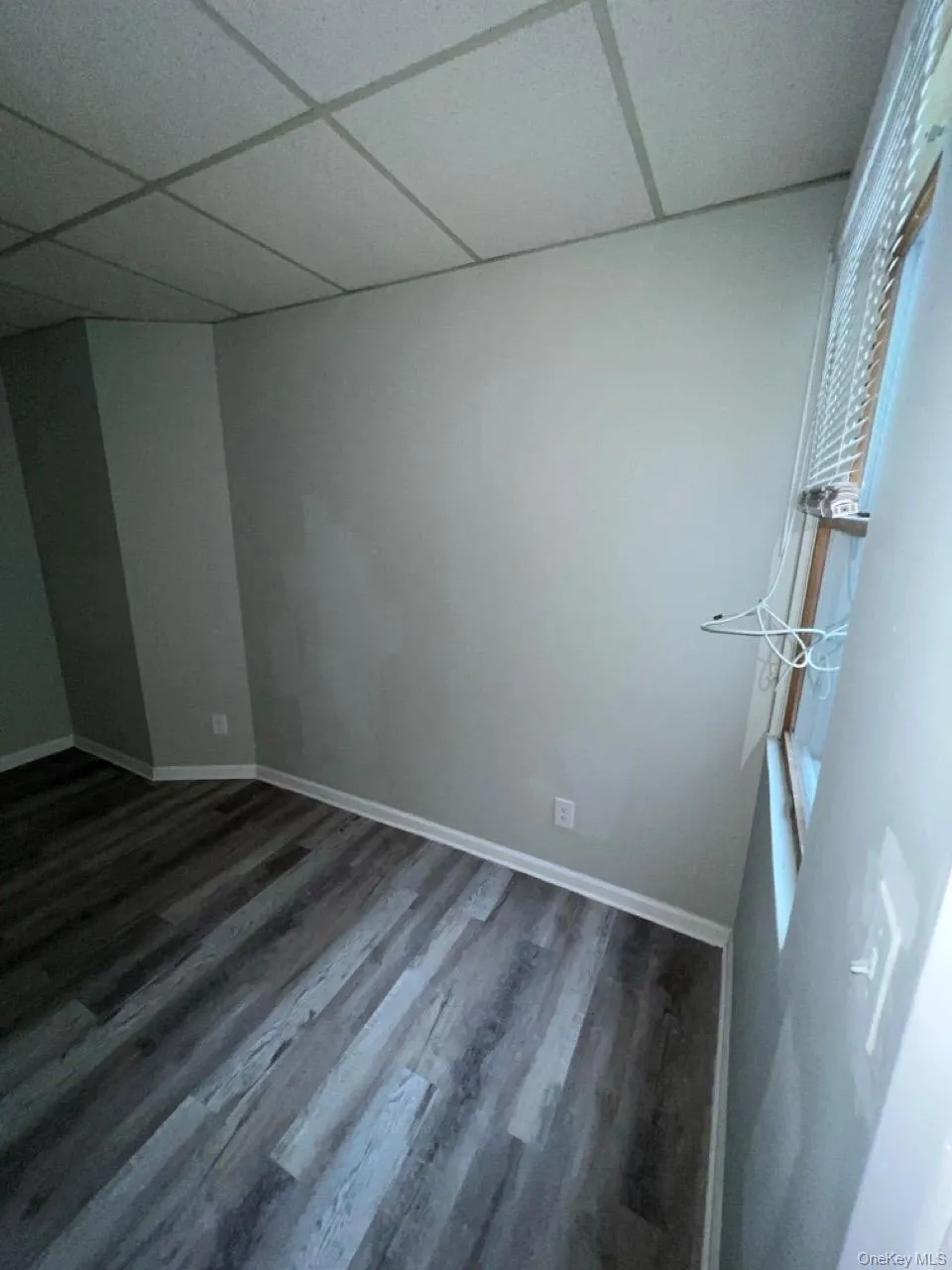 Unfurnished room with wood finished floors and a paneled ceiling Unfurnished room with wood finished floors and a paneled ceiling